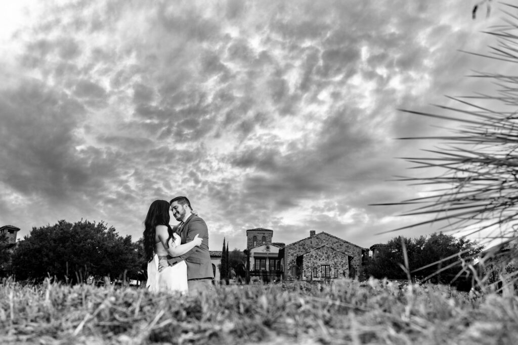 Black and white engagement photo in front of The Club at Bella Collina
