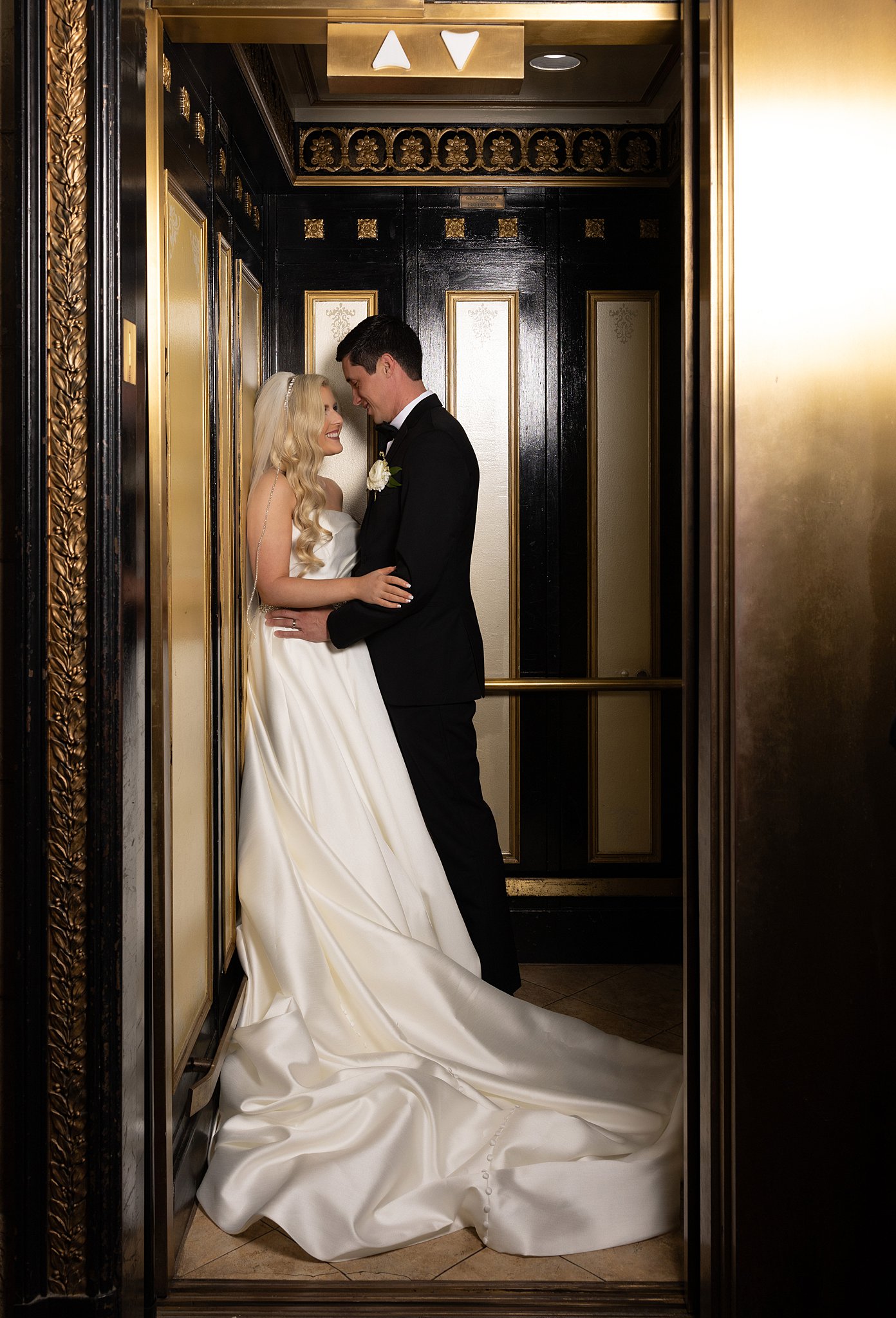 Newlyweds share an intimate moment against the wall of an ornate elevator in the Treasury on the Plaza Wedding venue