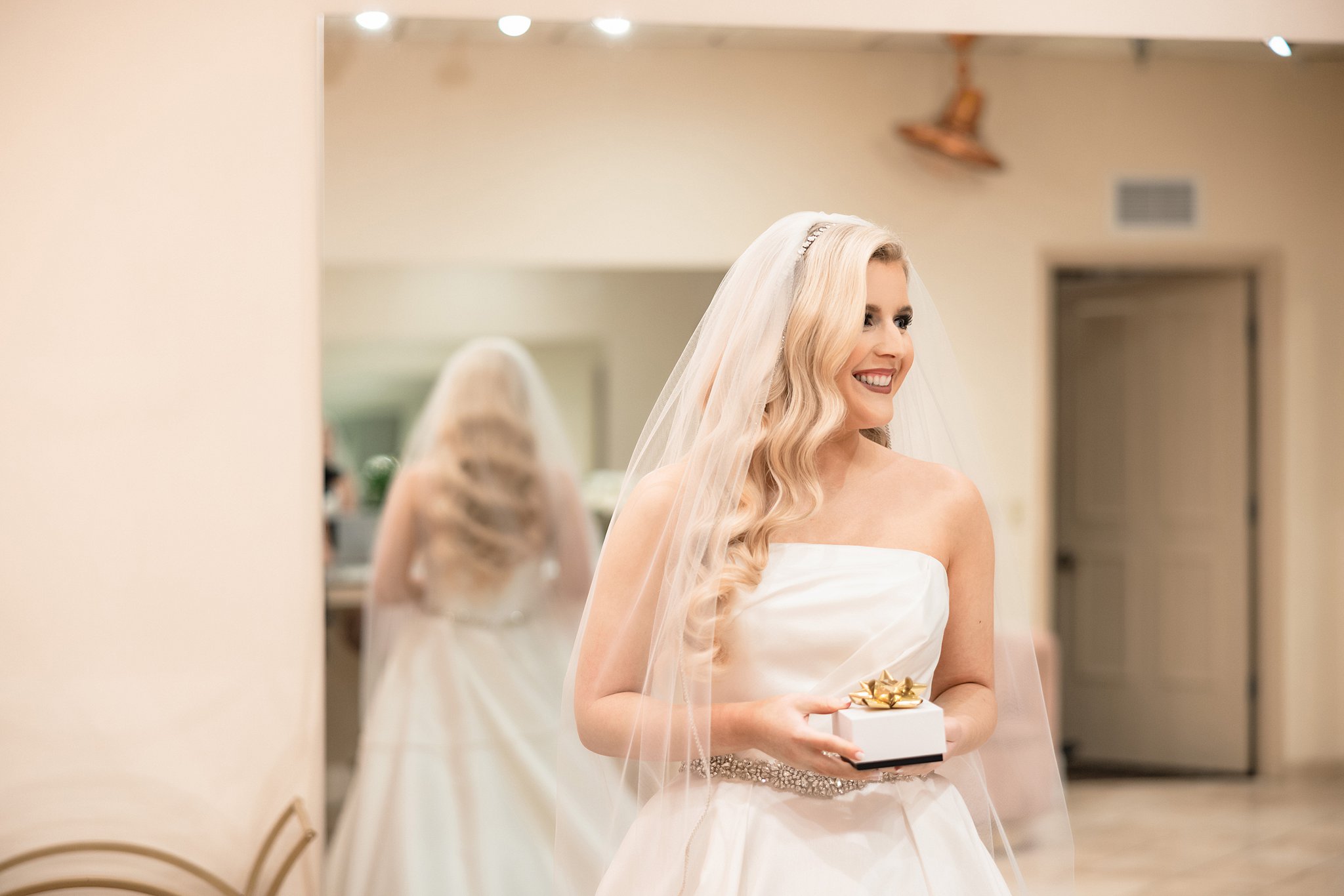 A bride opens a present in her getting ready room after getting dressed