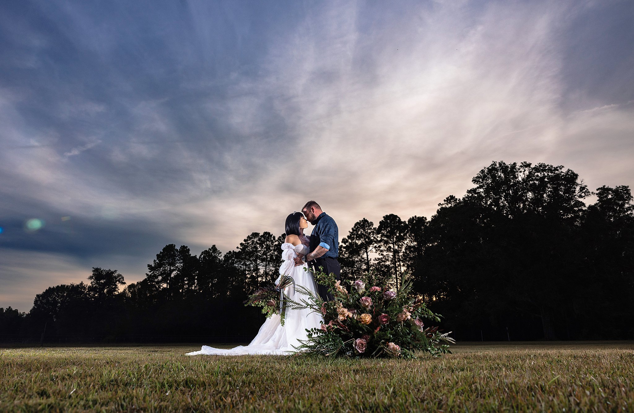 Newlyweds lean in for a kiss in an open field with an epic Florida sunset