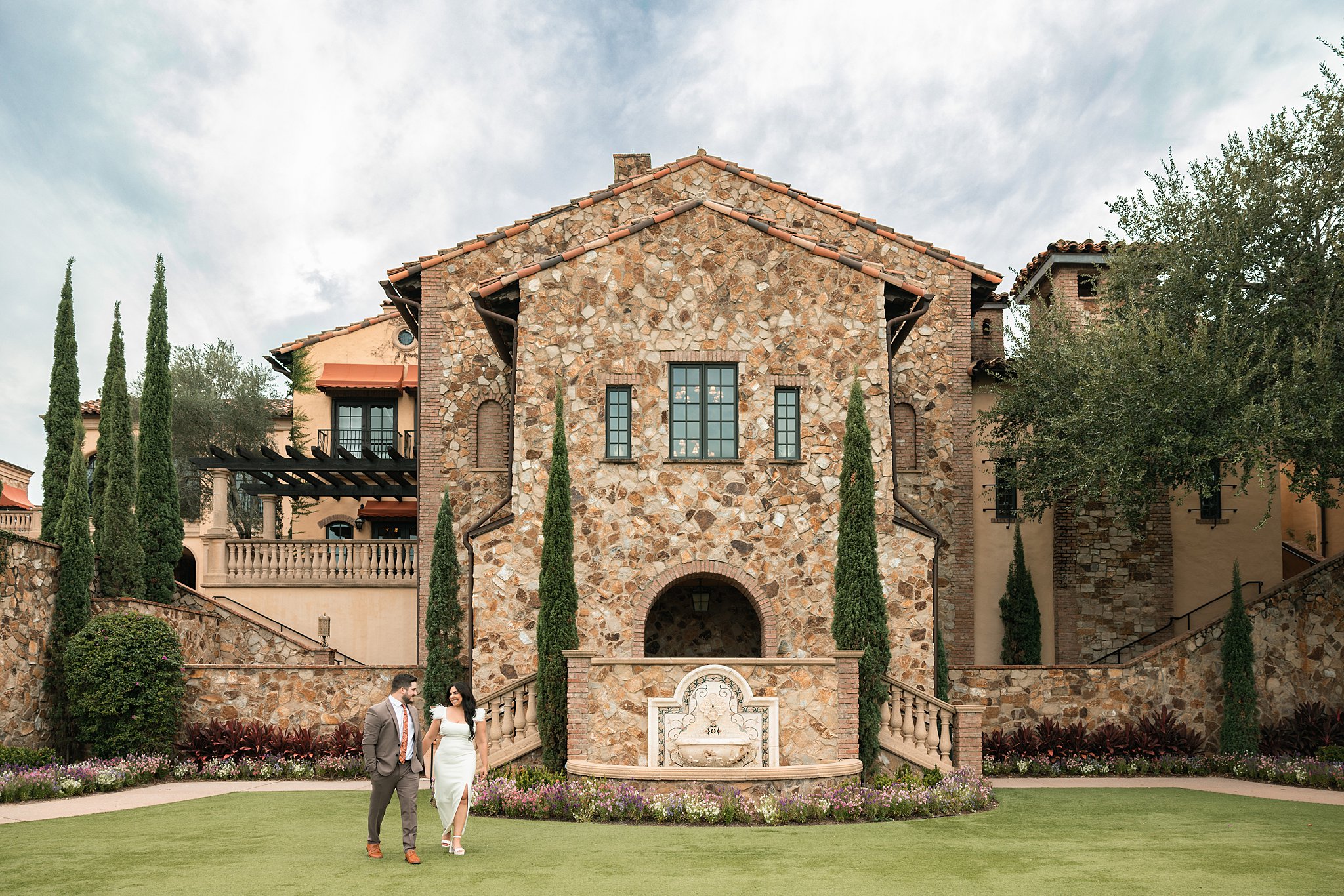 Newlyweds walk through a garden lawn at the side of their the club at bella collina wedding