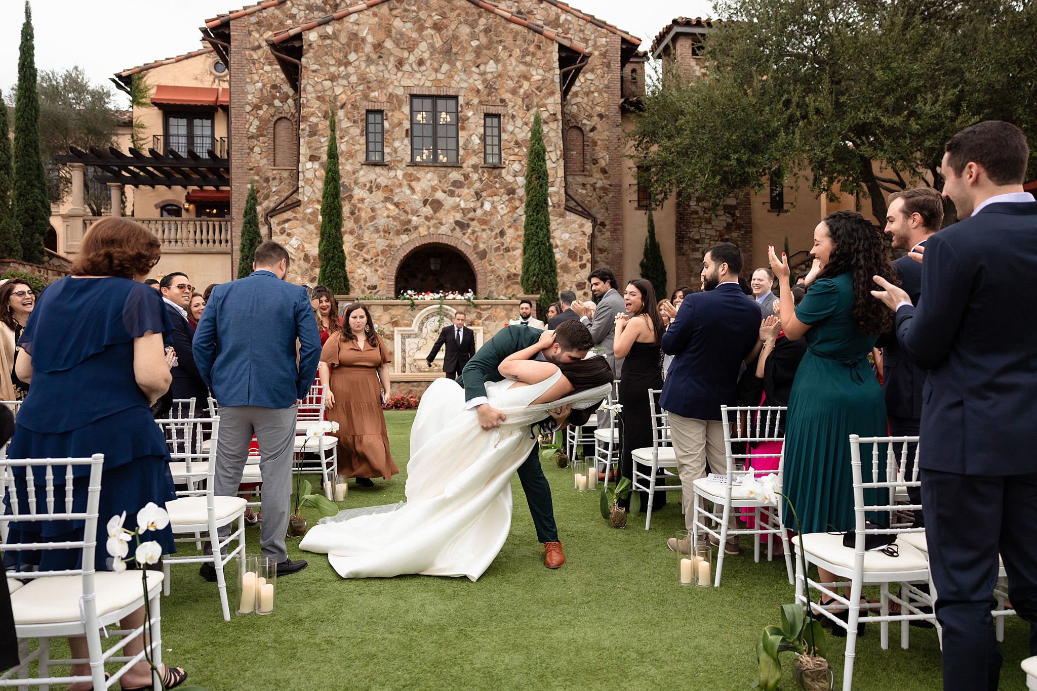 Newlyweds dip and kiss in the aisle of their lawn ceremony at the club at bella collina wedding venue