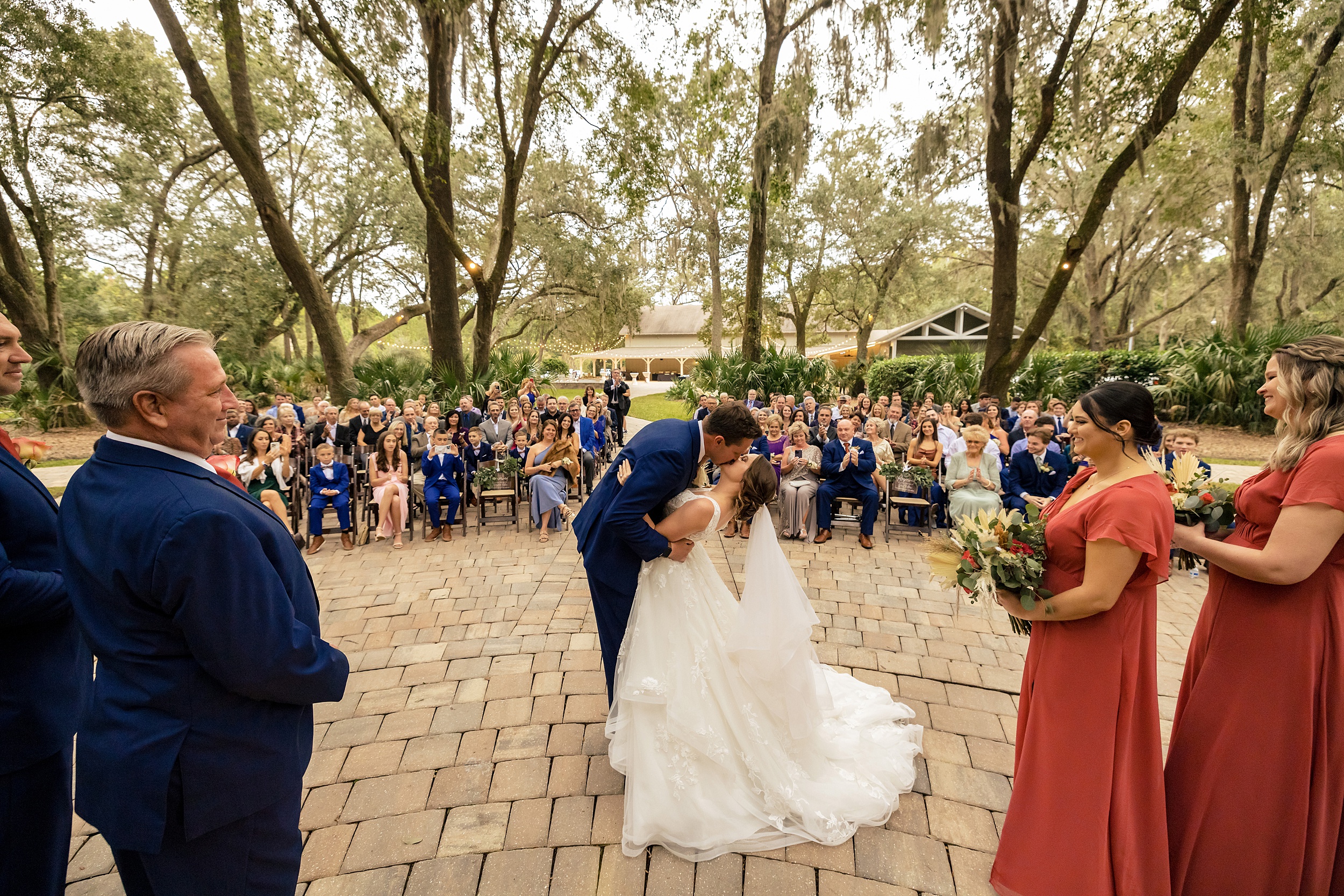 Newlyweds kiss at the end of their bowing oaks wedding ceremony to applause from the guests