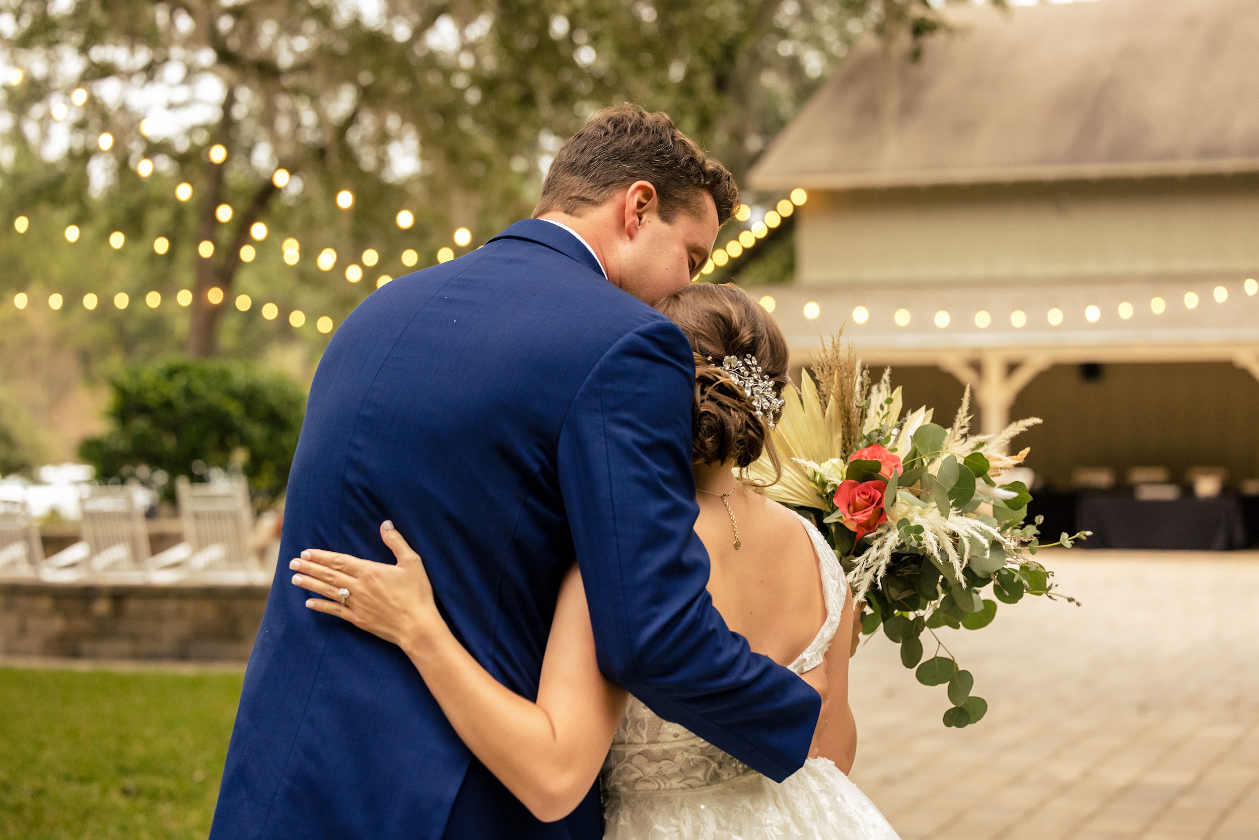 Newlyweds stand together with arms around each other on the patio of their wedding venue