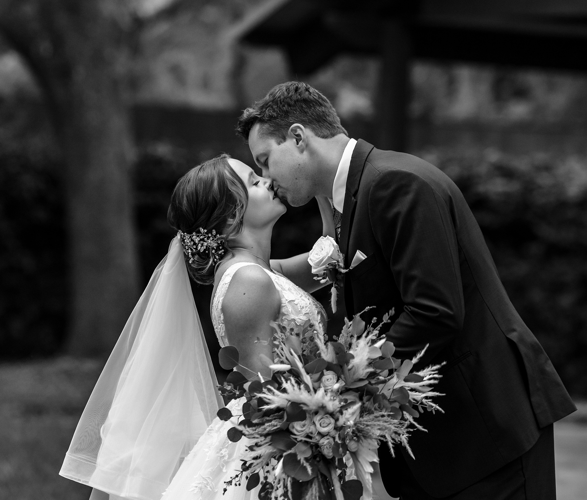 Newlyweds kiss on a patio under oak trees