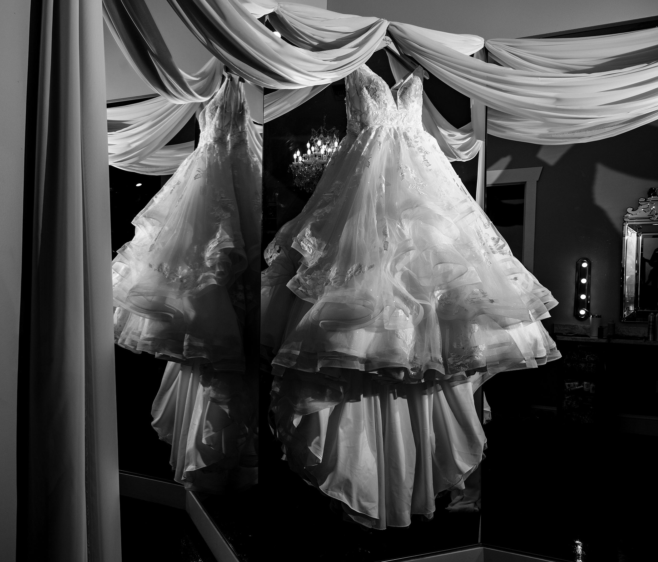 A lace wedding dress hangs on mirrors in the bowing oaks wedding venue getting ready room