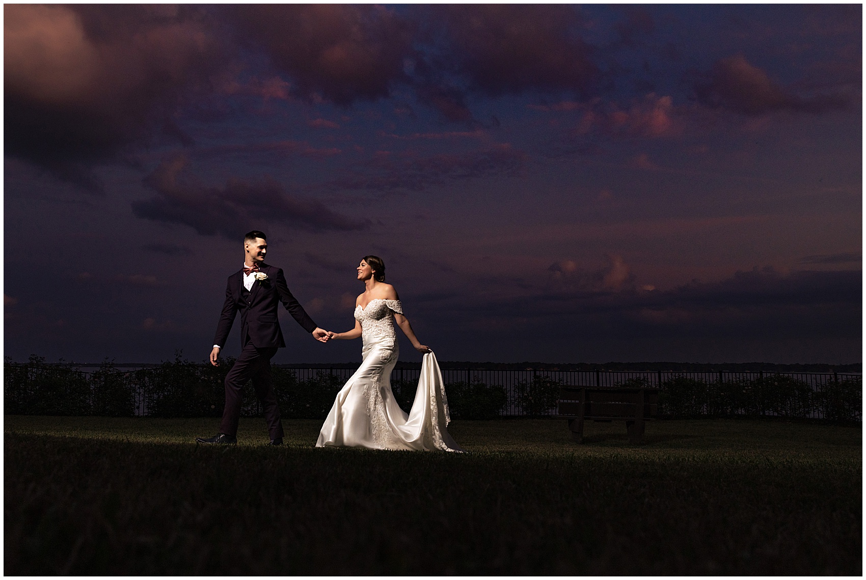 Newlyweds walk across a lawn at sunset holding hands at their club continental wedding