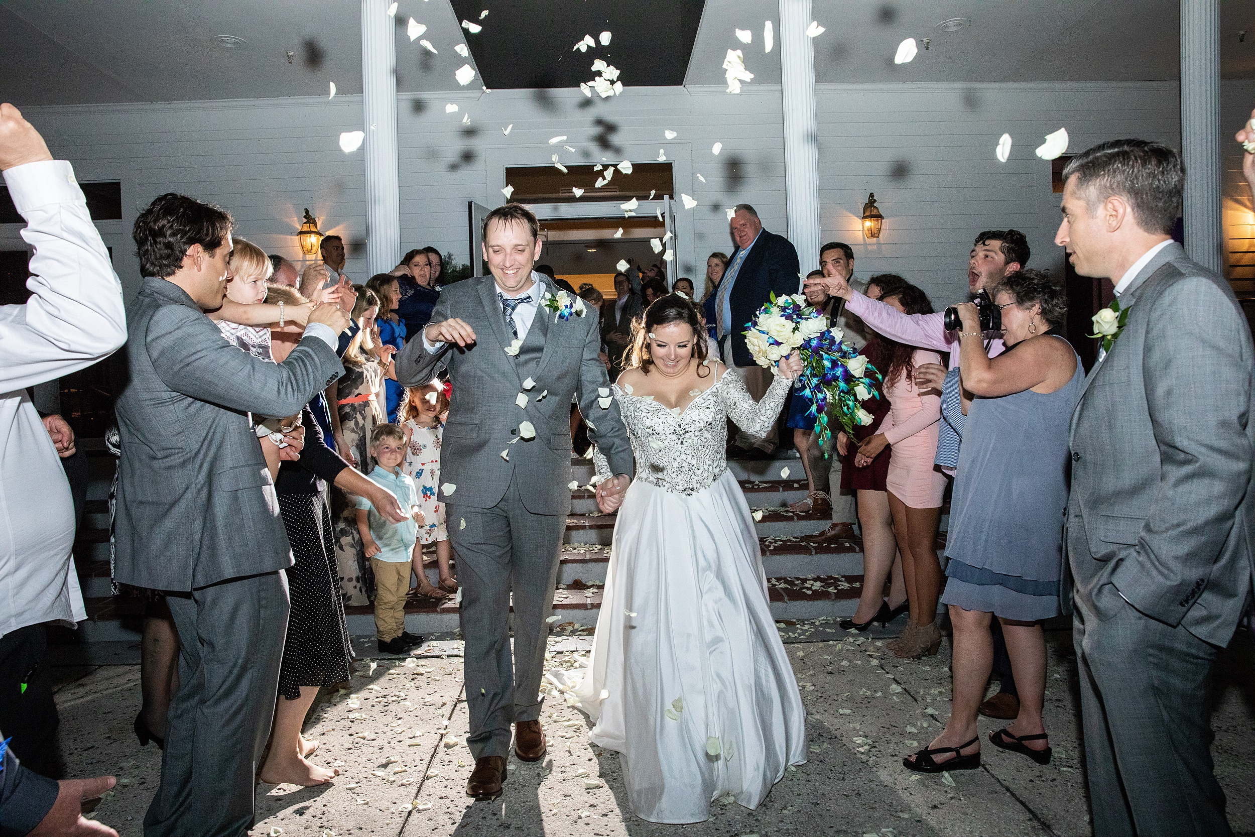 Newlyweds exit their deercreek country club wedding reception surrounded by guests throwing white rose petals