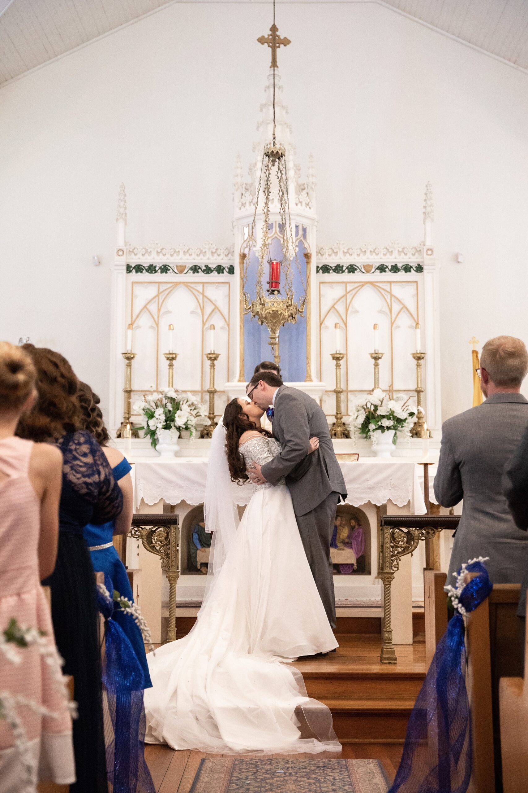 Newlyweds kiss at the altar of their wedding ceremony to applause from guests