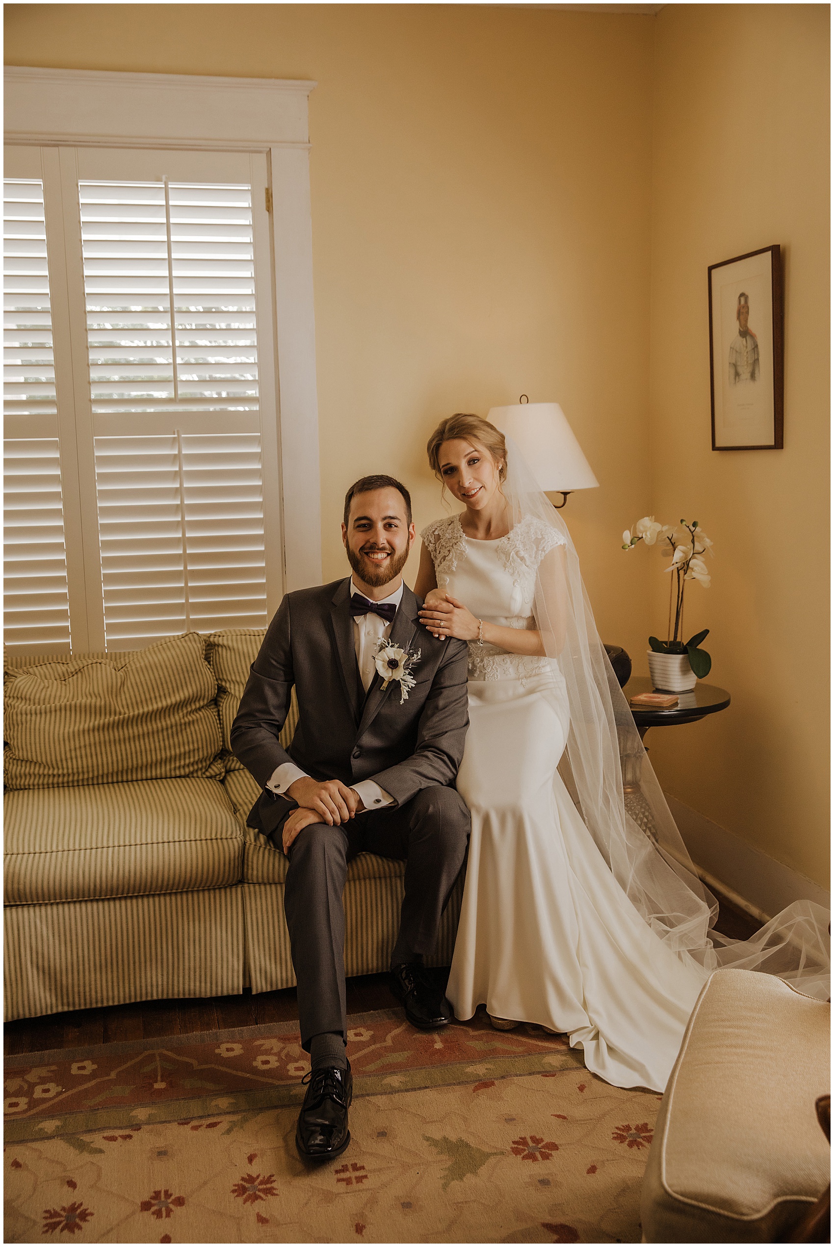 Newlywed sit together on an antique couch in the bridal suite