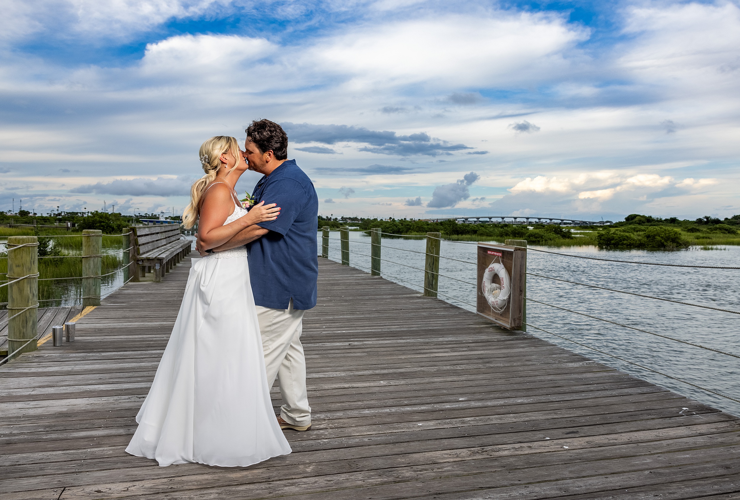 Newlyweds kiss on a river boardwalk