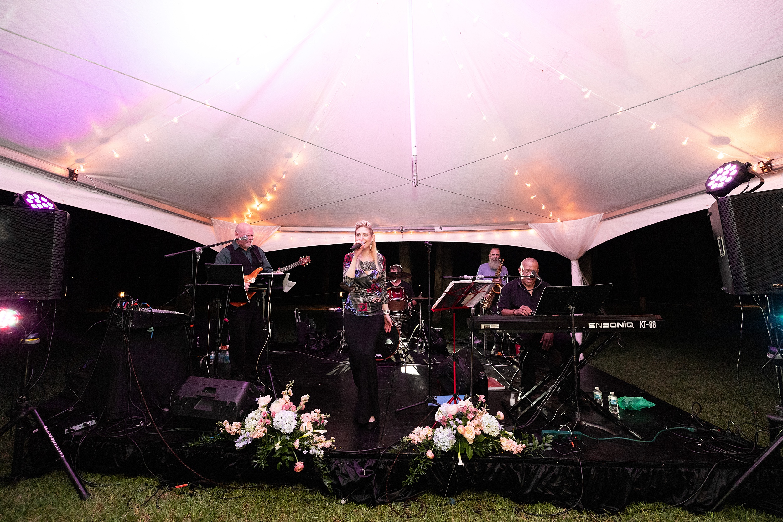 A band plays under a white tent on a stage