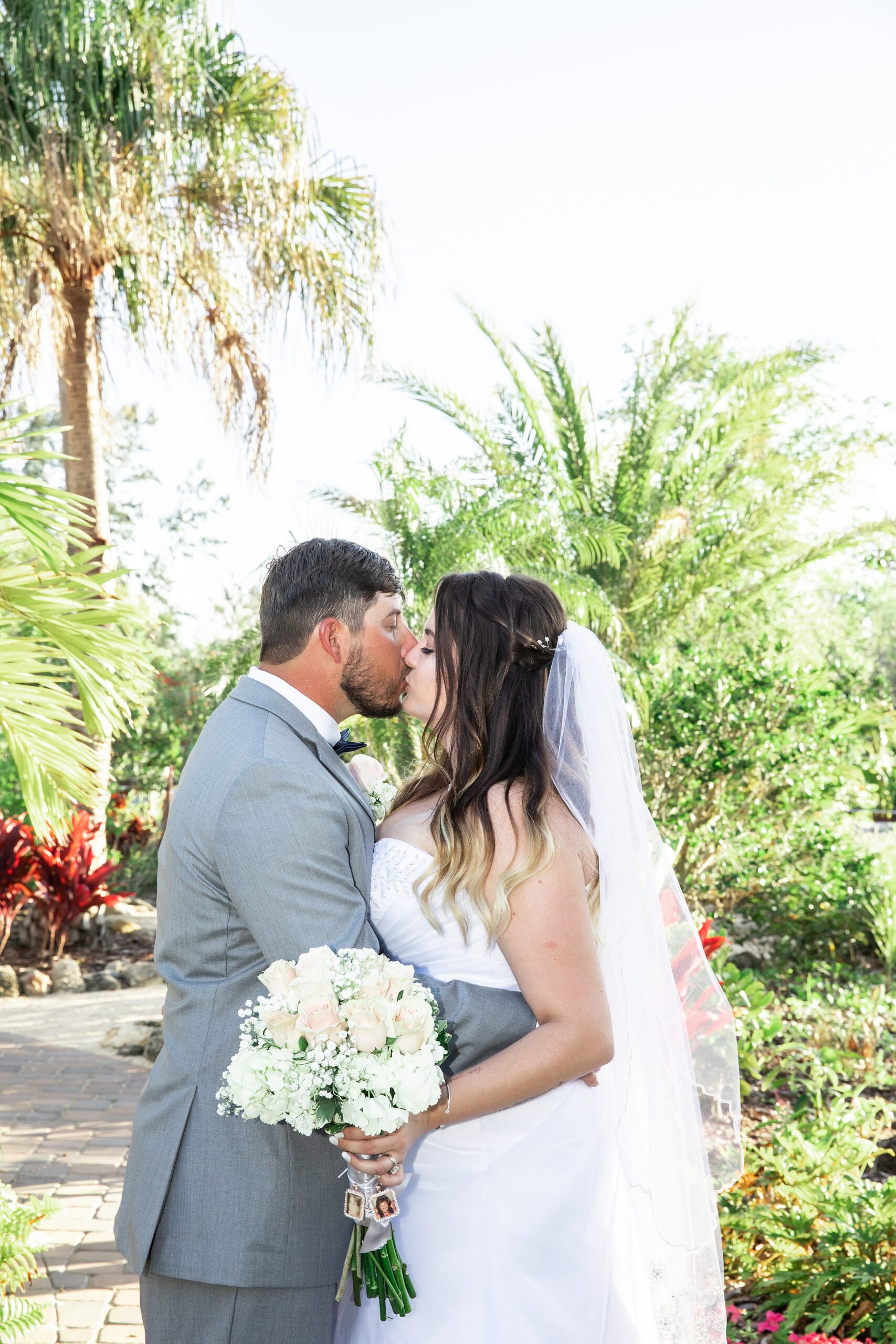 Newlyweds kiss while standing in a garden at their historic grant station wedding
