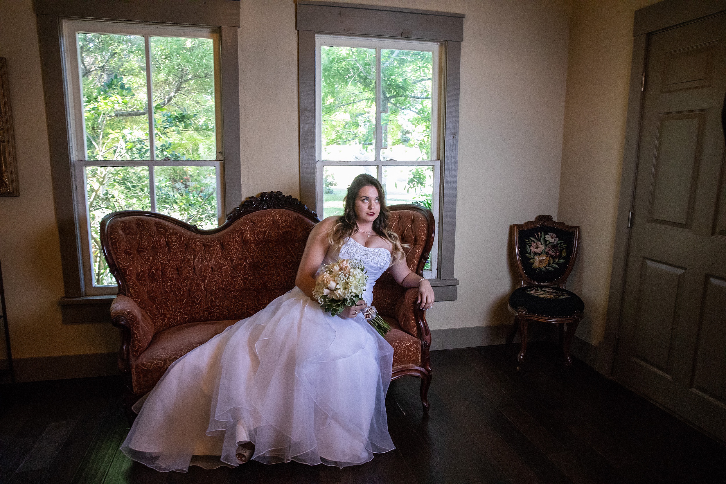 A bride sits across an antique couch during her historic grant station wedding