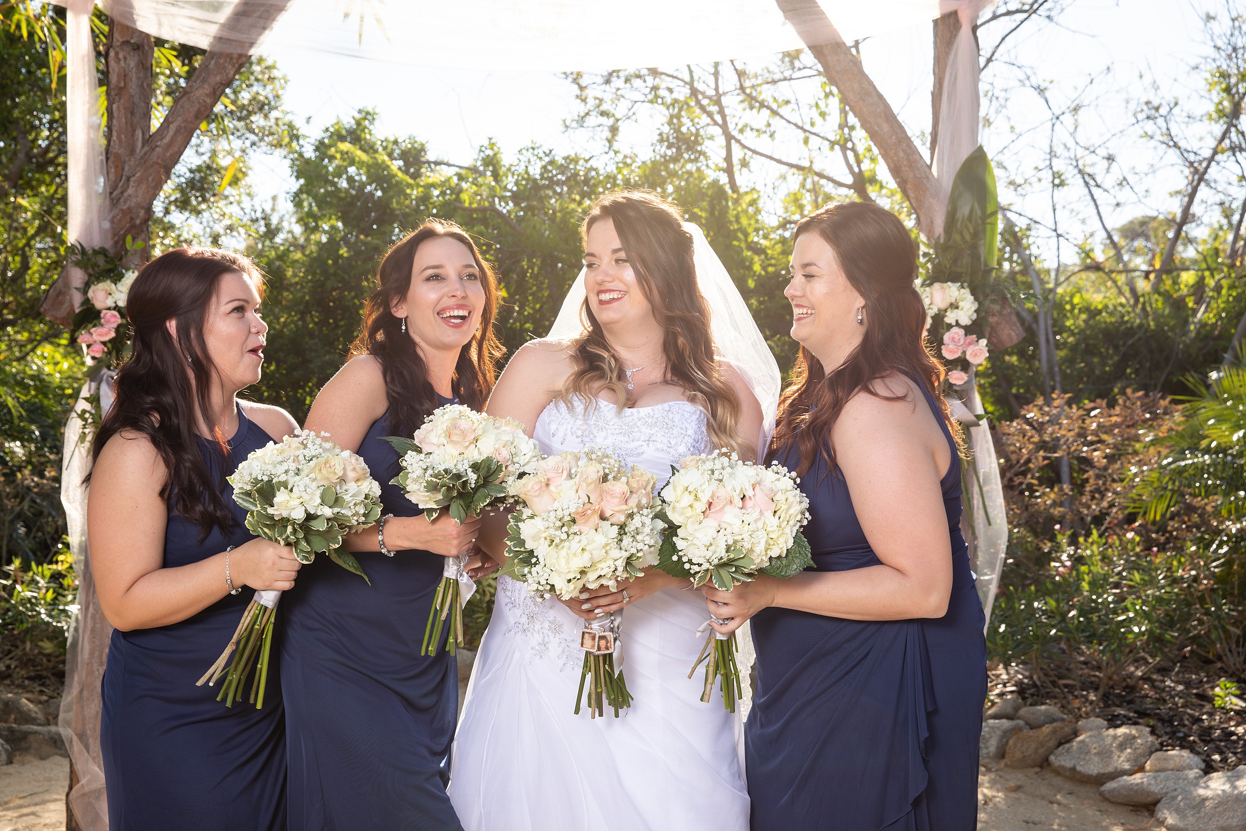 A bride laughs while holding her bouquet with her bridesmaids at her historic grant station wedding