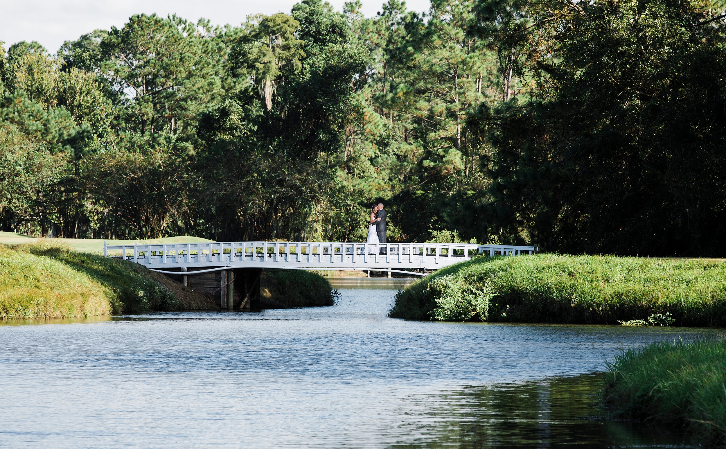 Newlyweds share a quiet intimate moment on a golf course bridge during their first look at their magnolia point wedding