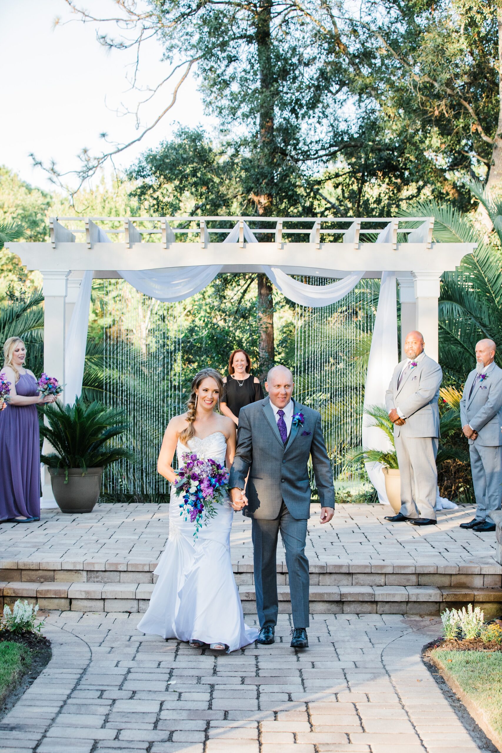 Newlyweds walk up the aisle holding hands at the end of their outdoor magnolia point wedding ceremony