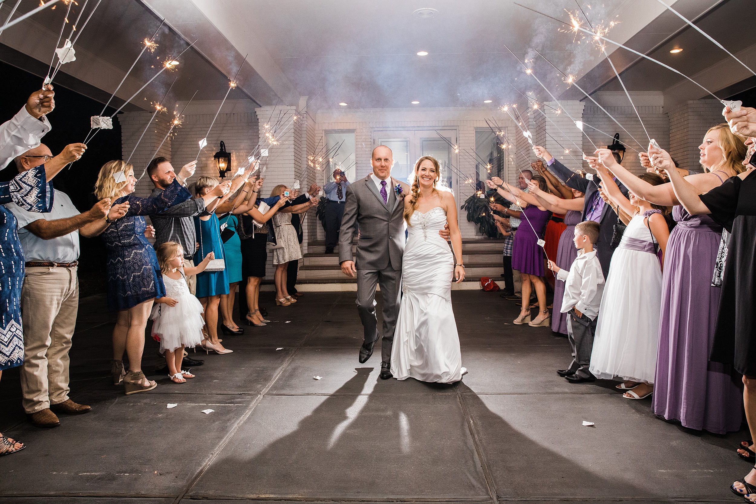 Newlyweds exit their magnolia point wedding reception to a crowd holding up sparklers