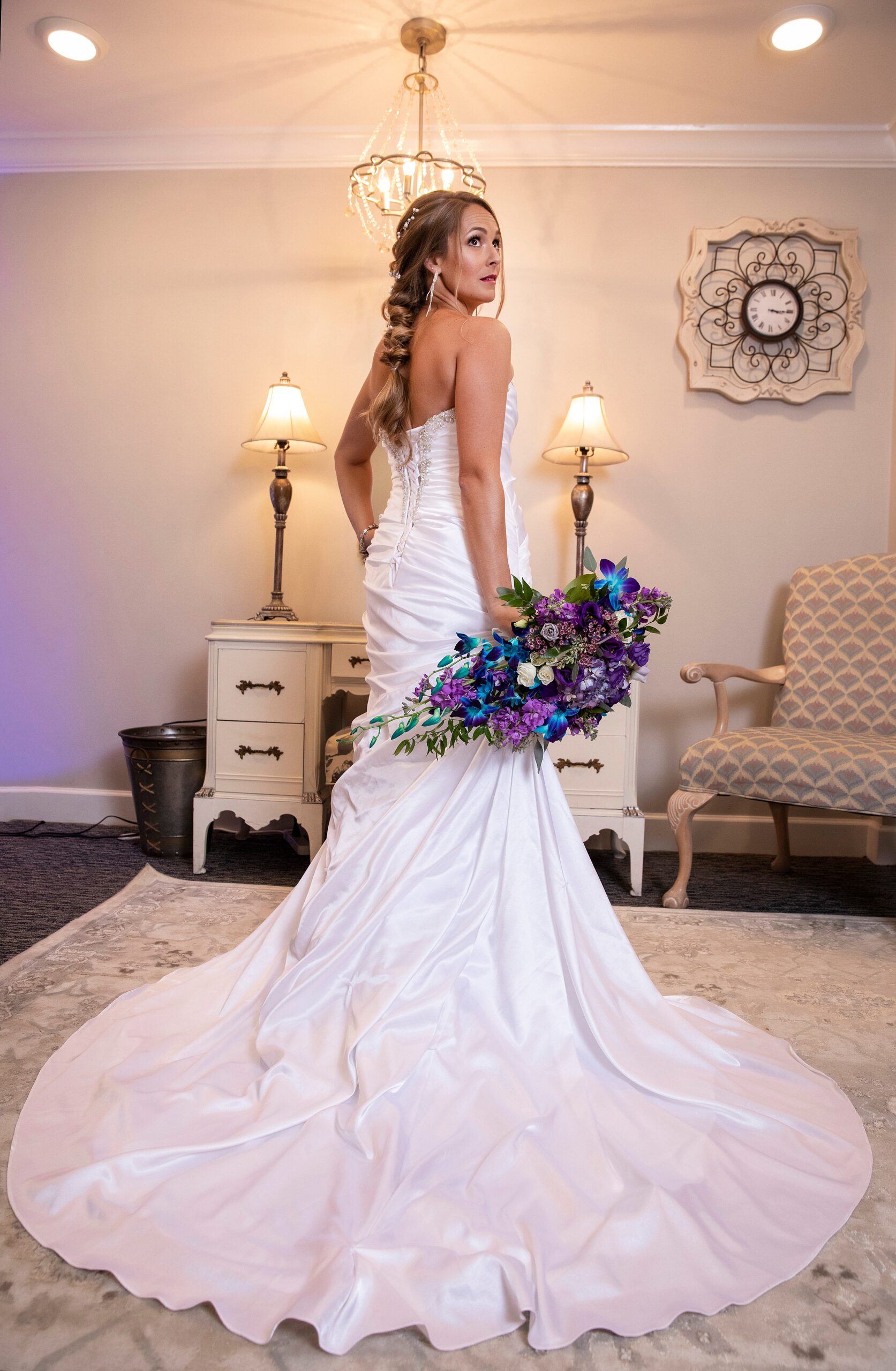 A bride looks over her shoulder while standing in the getting ready room with her train fully spread