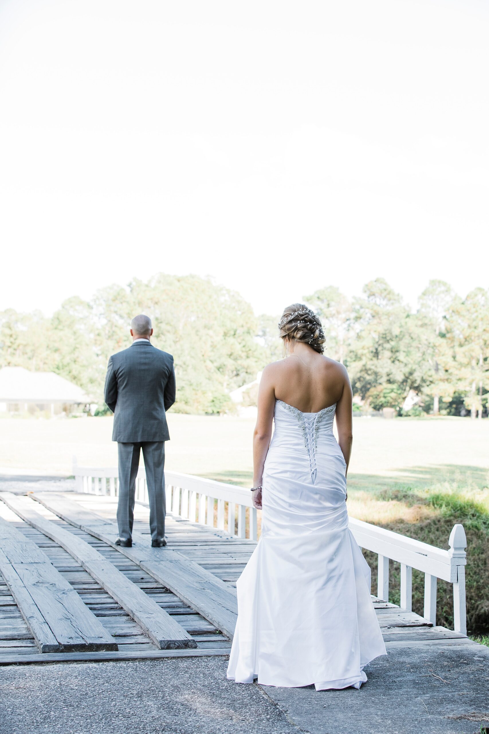 A bride walks onto a wooden golf course bridge to her magnolia point wedding first look