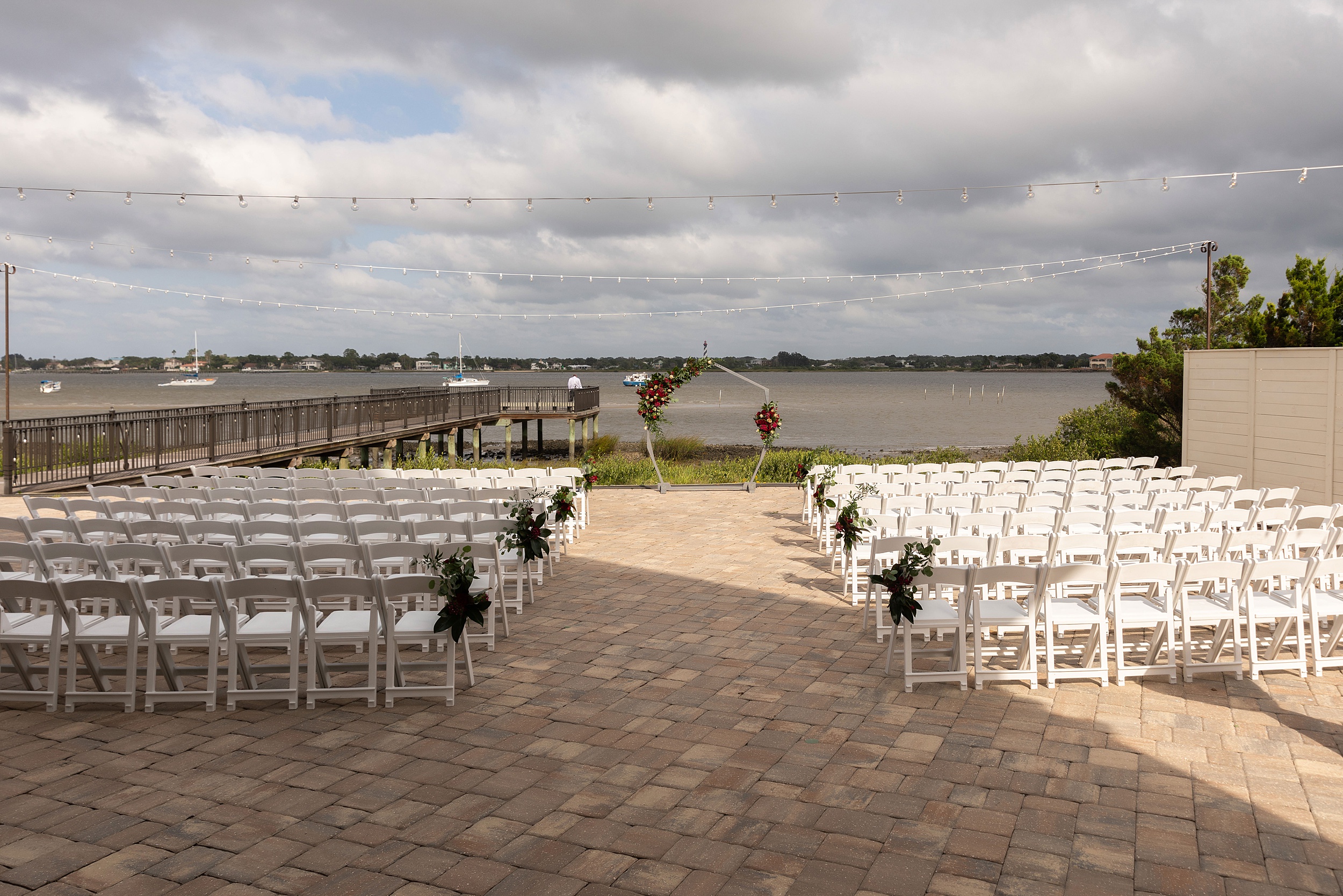 Details of a river house events wedding ceremony set up with white chairs on a riverfront patio