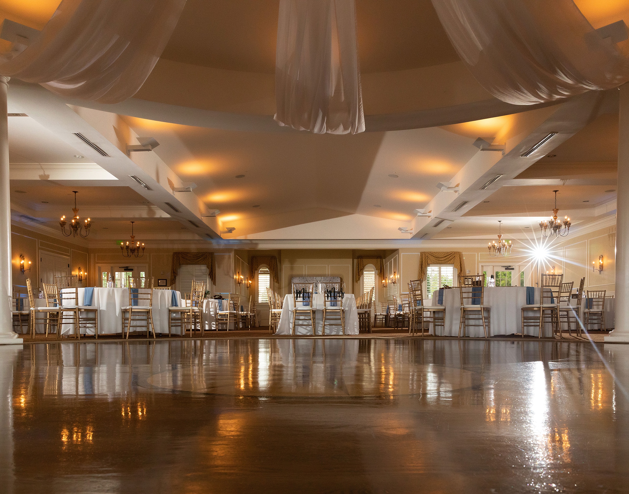 Details of a river house events wedding reception set up with gold chairs and white linens
