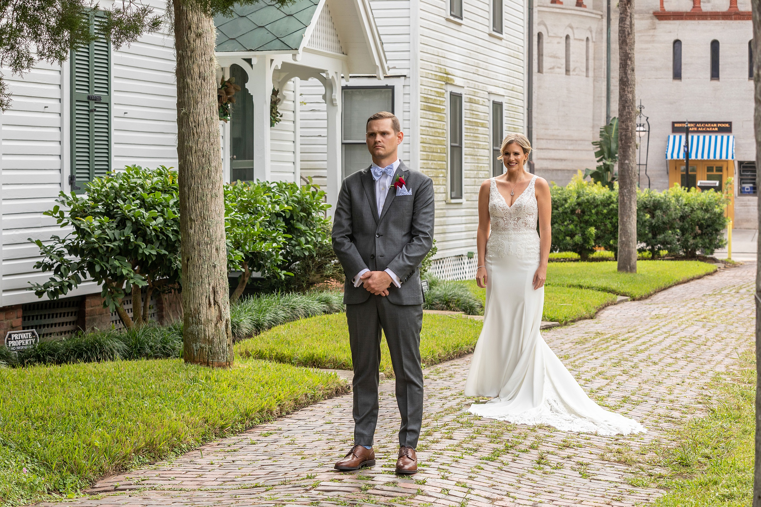 A groom waits for his bride to call him to see her for the first time in a first look on a historical brick sidewalk