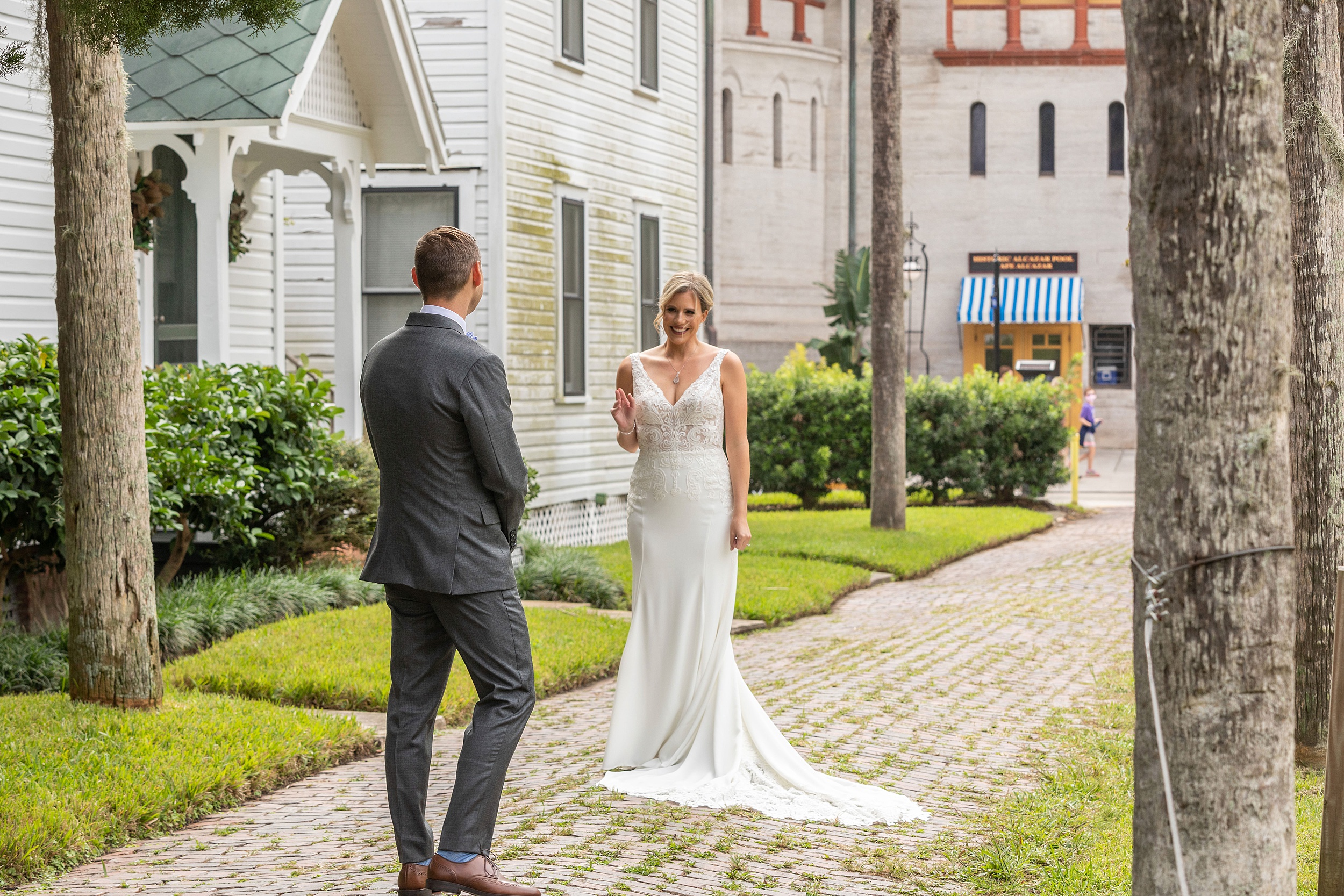 A bride waves to her groom as he sees her in her dress for the first time