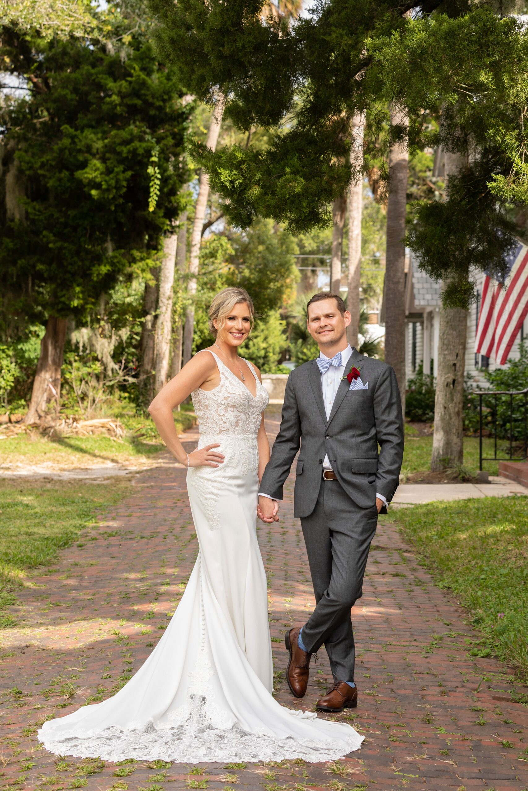 Newlyweds stand in a brick sidewalk holding hands at their river house events wedding