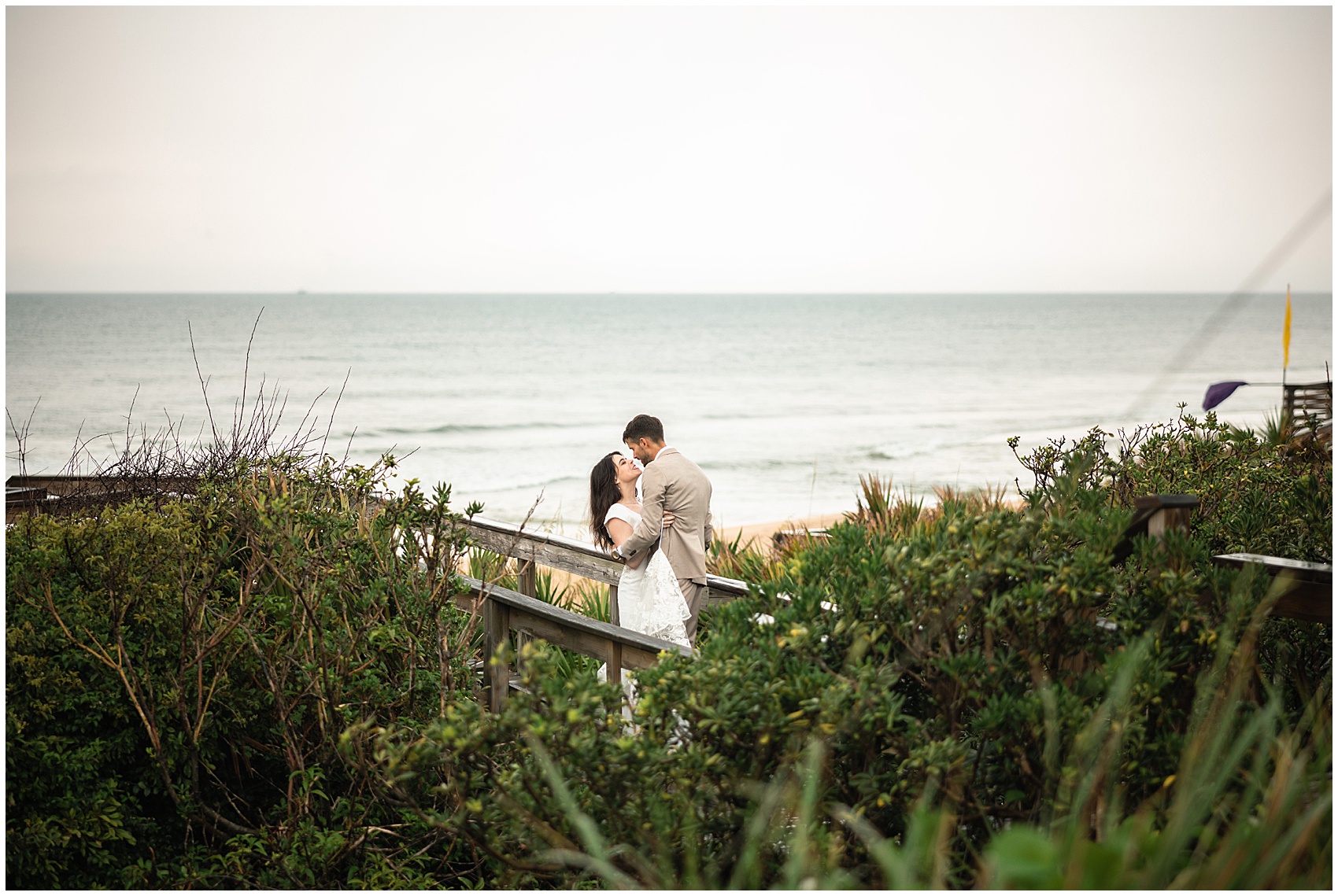 Newlyweds share an intimate moment on an empty beach boardwalk at their serenata beach club wedding