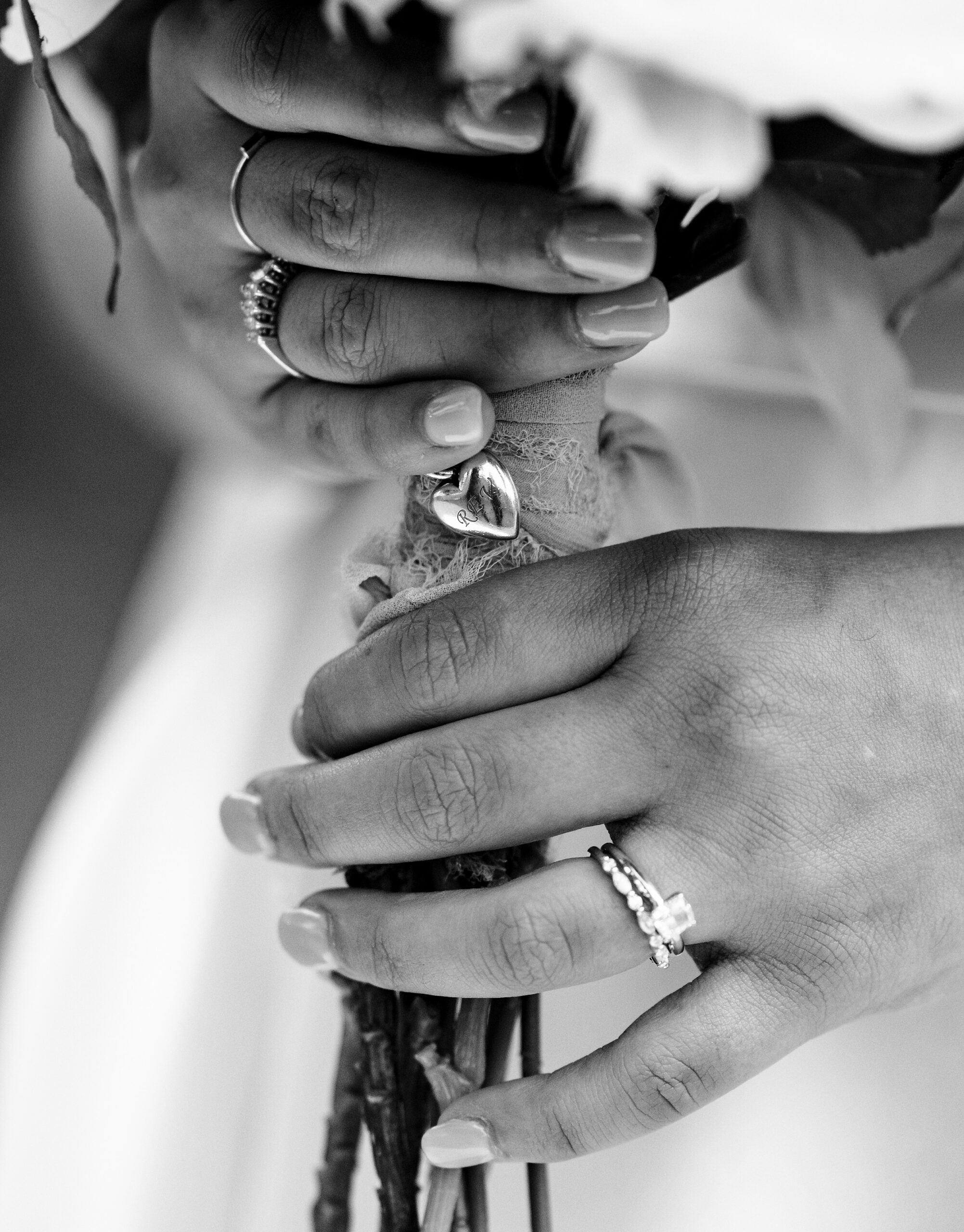 Details of a bride's hands holding a bouquet with a locket