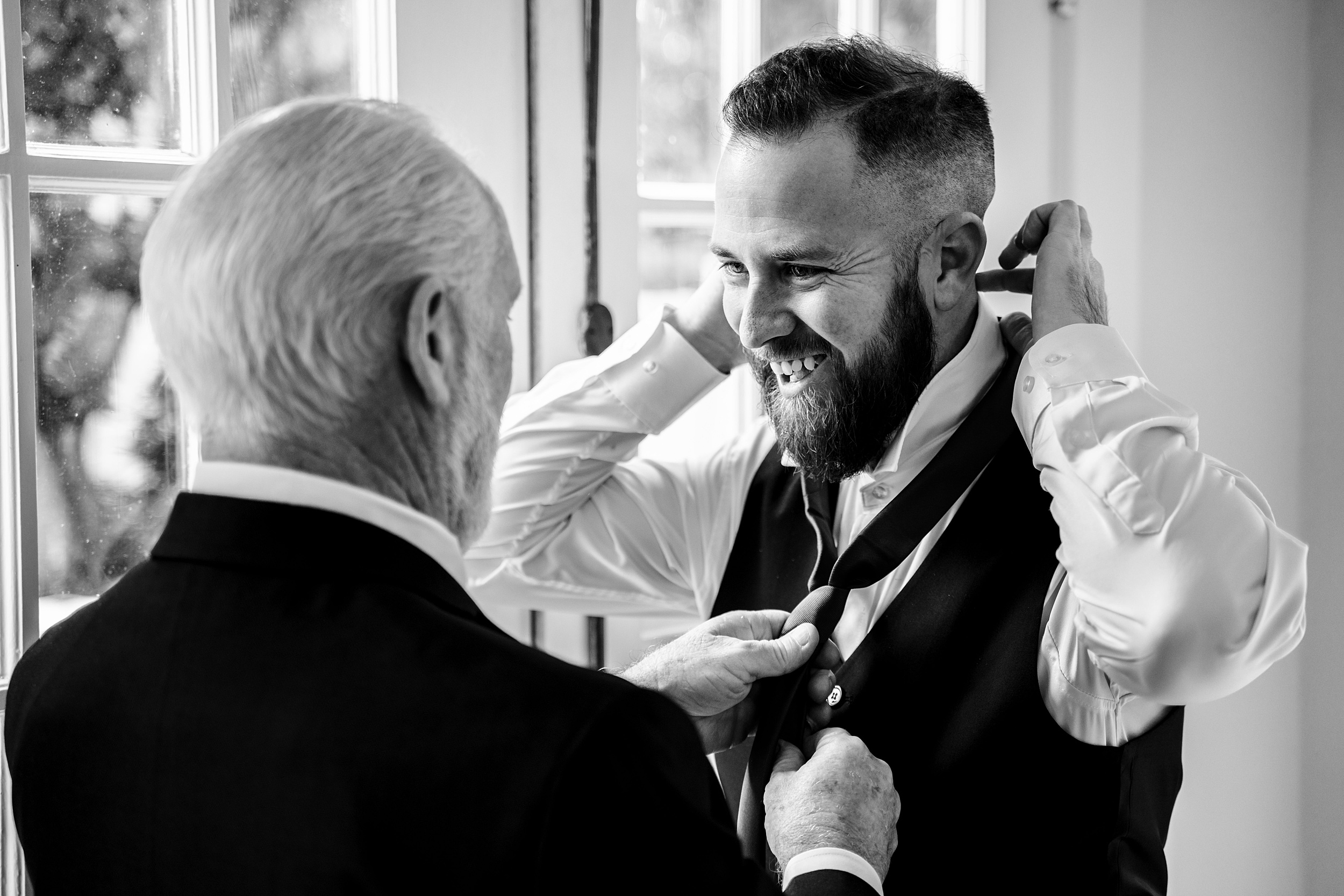 A groom is helped by dad to put on his tie at his 1010 west wedding