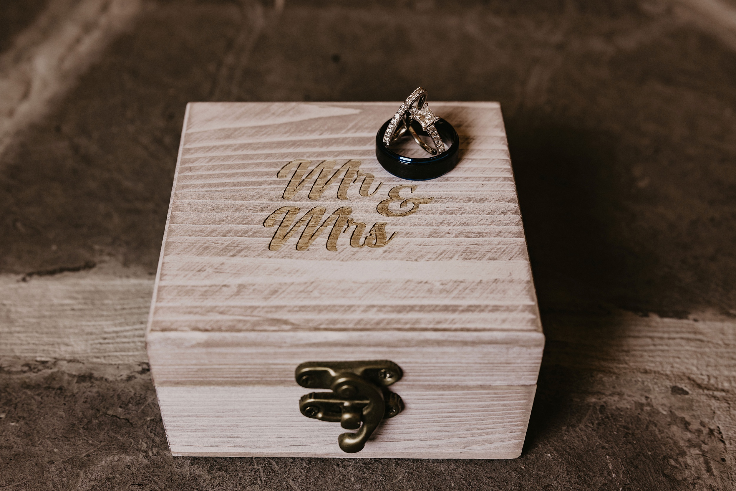 Details of a custom engraved wooden box with rings posed on top of it