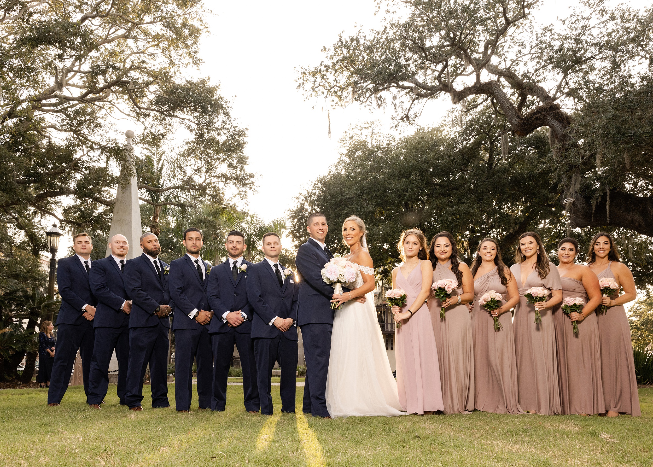 Newlyweds stand together while surrounded by their wedding party