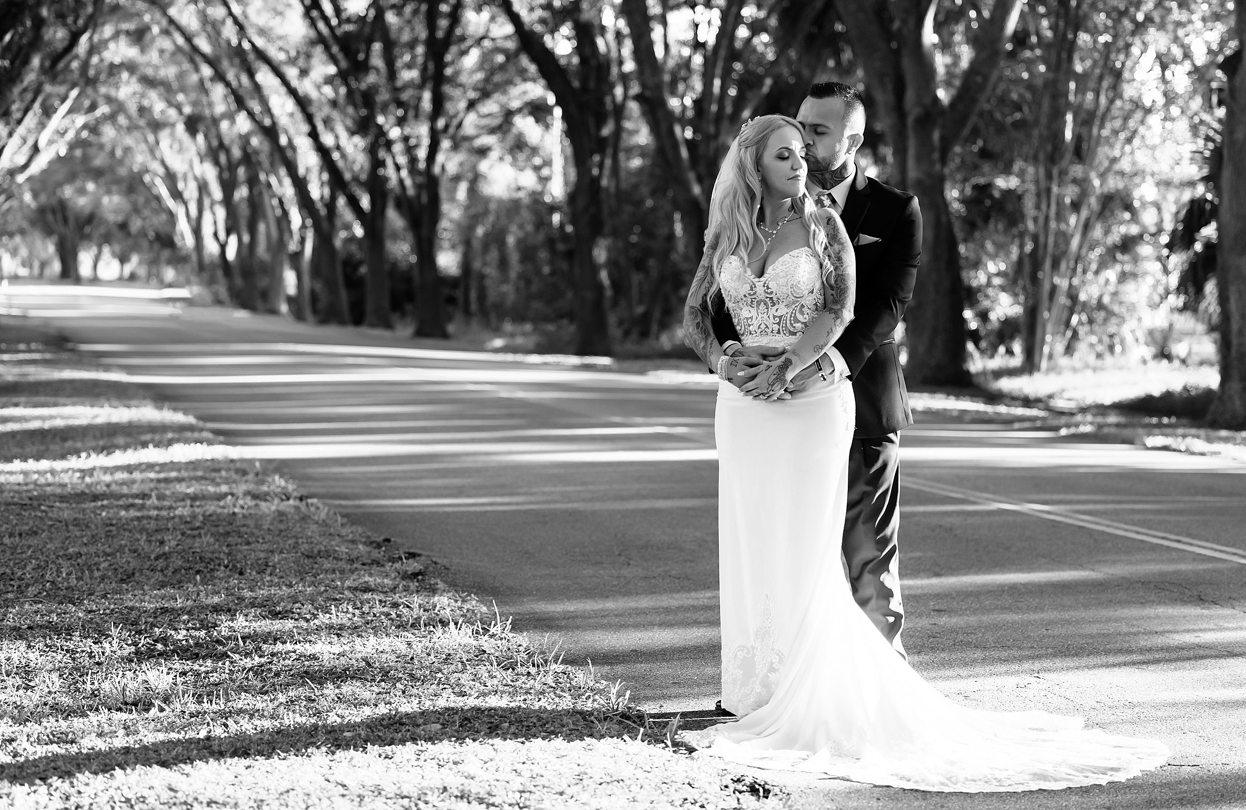 Newlyweds share an intimate moment under a line of oak trees