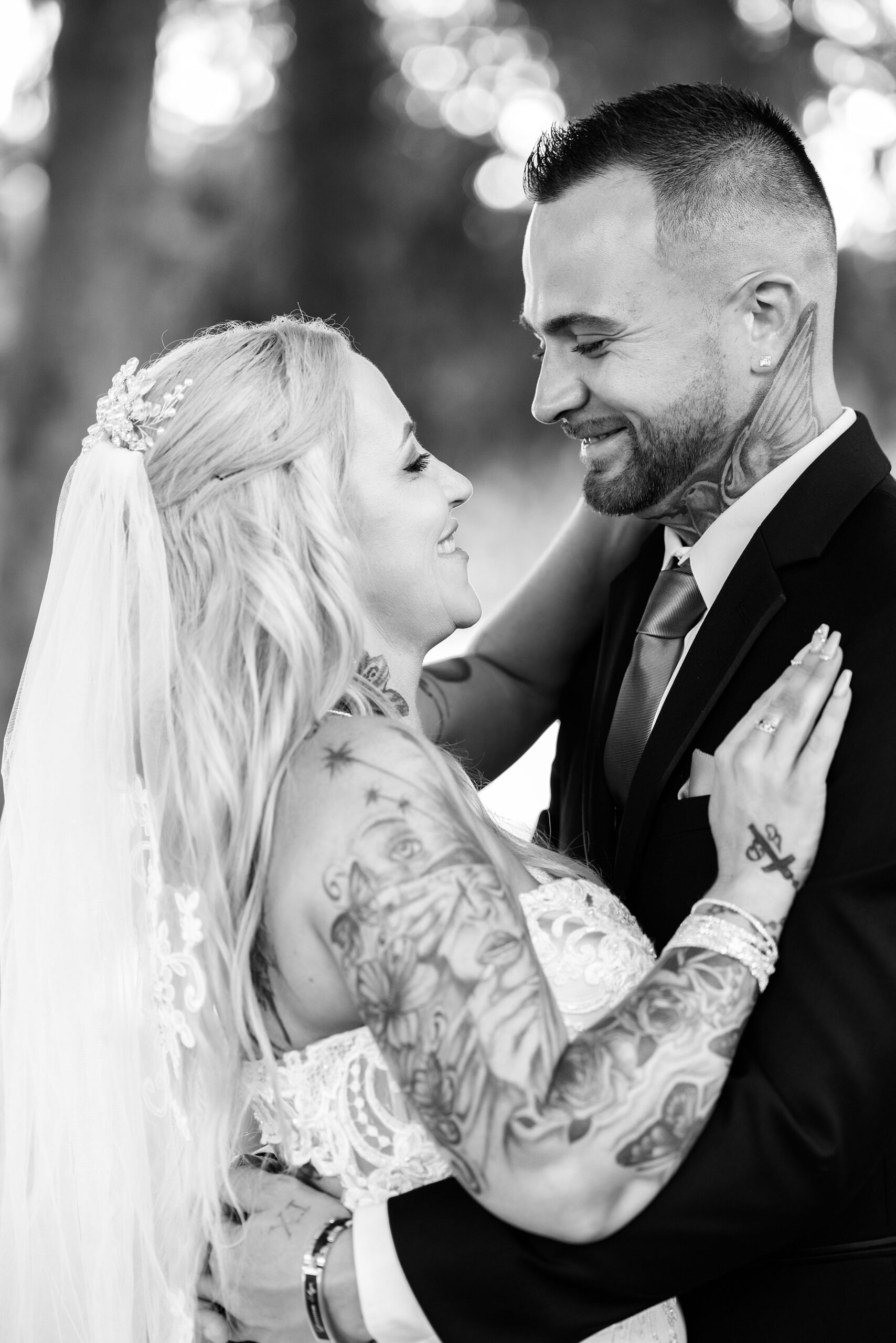 Newlyweds with tattoos embrace for a kiss while standing outside during their cypress grove estate house wedding