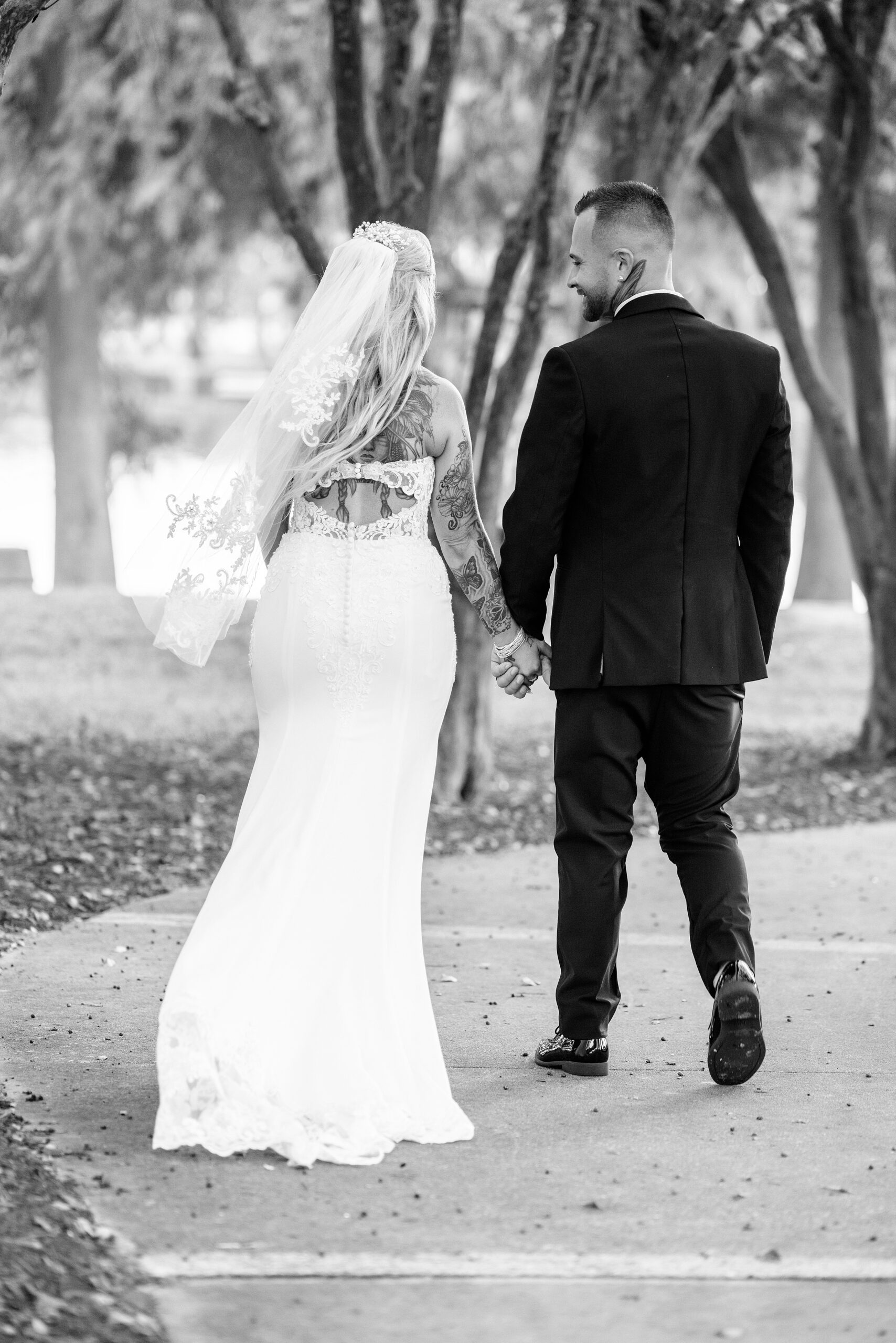 Newlyweds walk down a sidewalk holding hands at their cypress grove estate house wedding