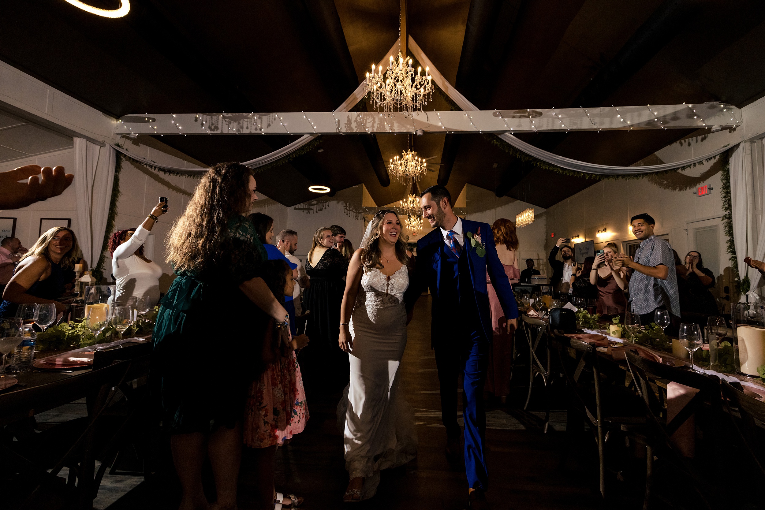 Newlyweds enter their wedding reception surrounded by guests