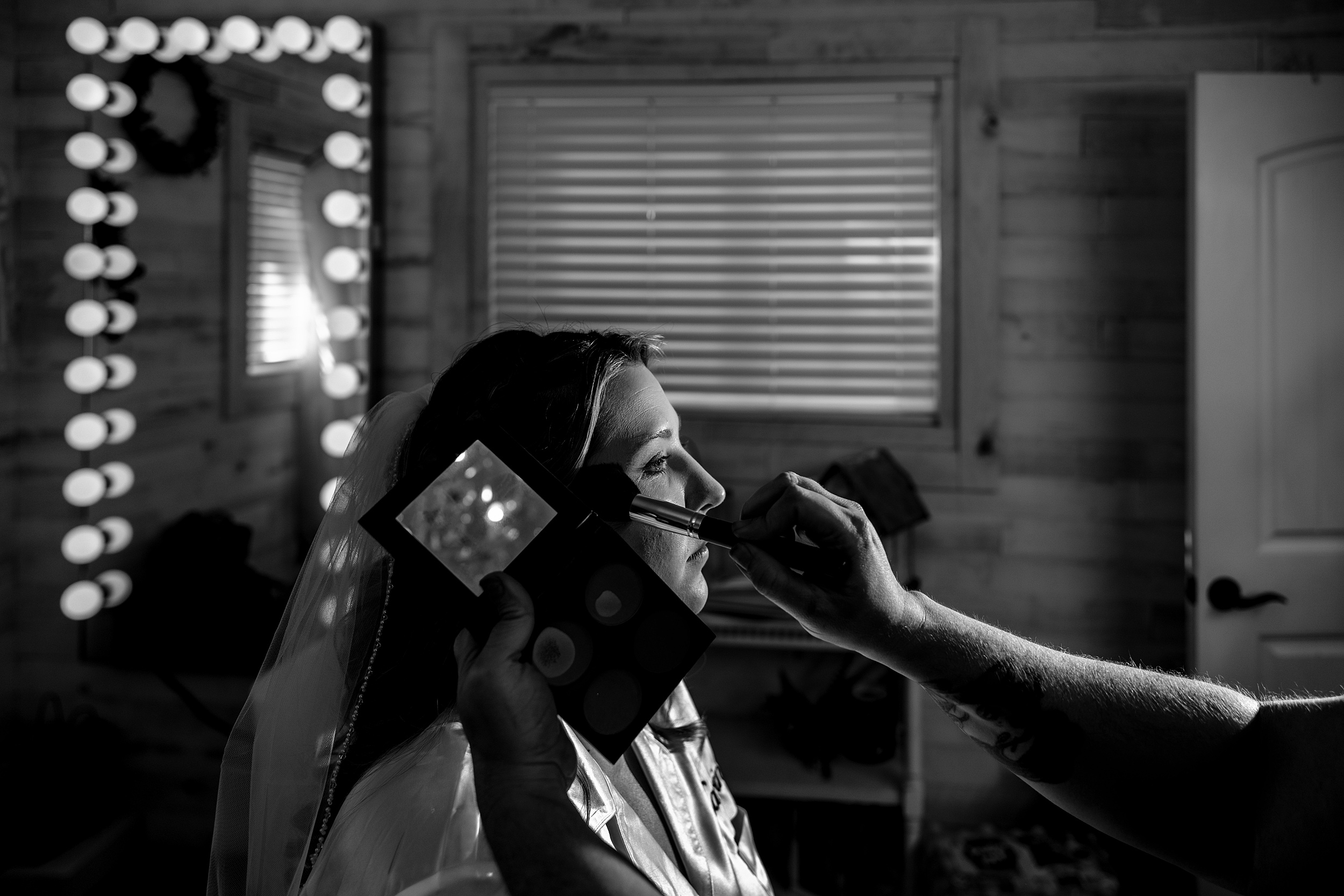 A bride sits while getting her makeup done