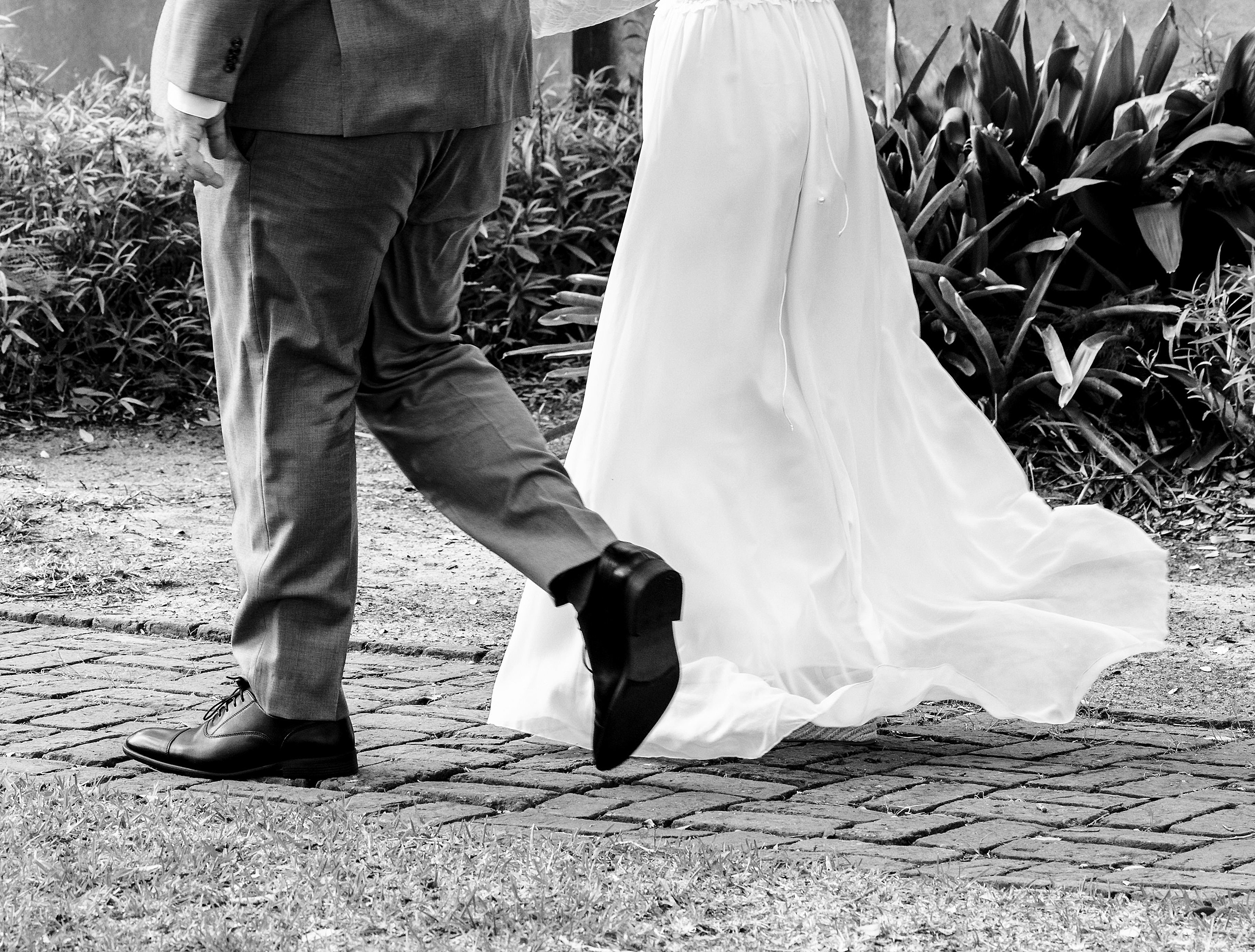 Newlyweds walk on a garden path holding hands