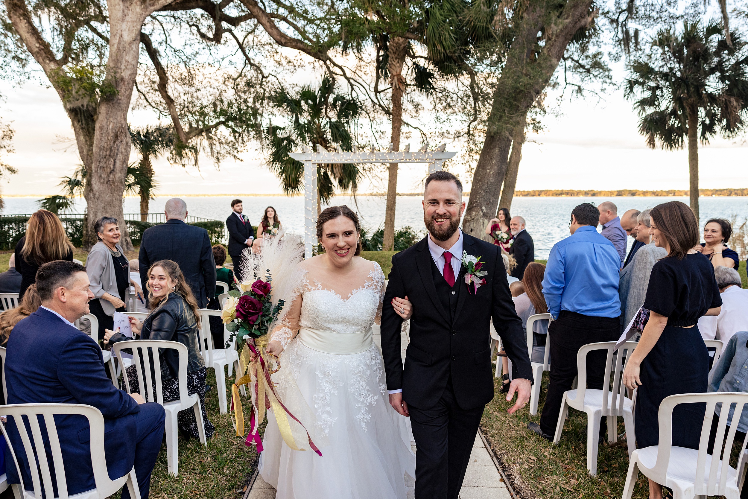 Newlyweds smile while walking up the aisle of their waterfront paradise cove wedding ceremony