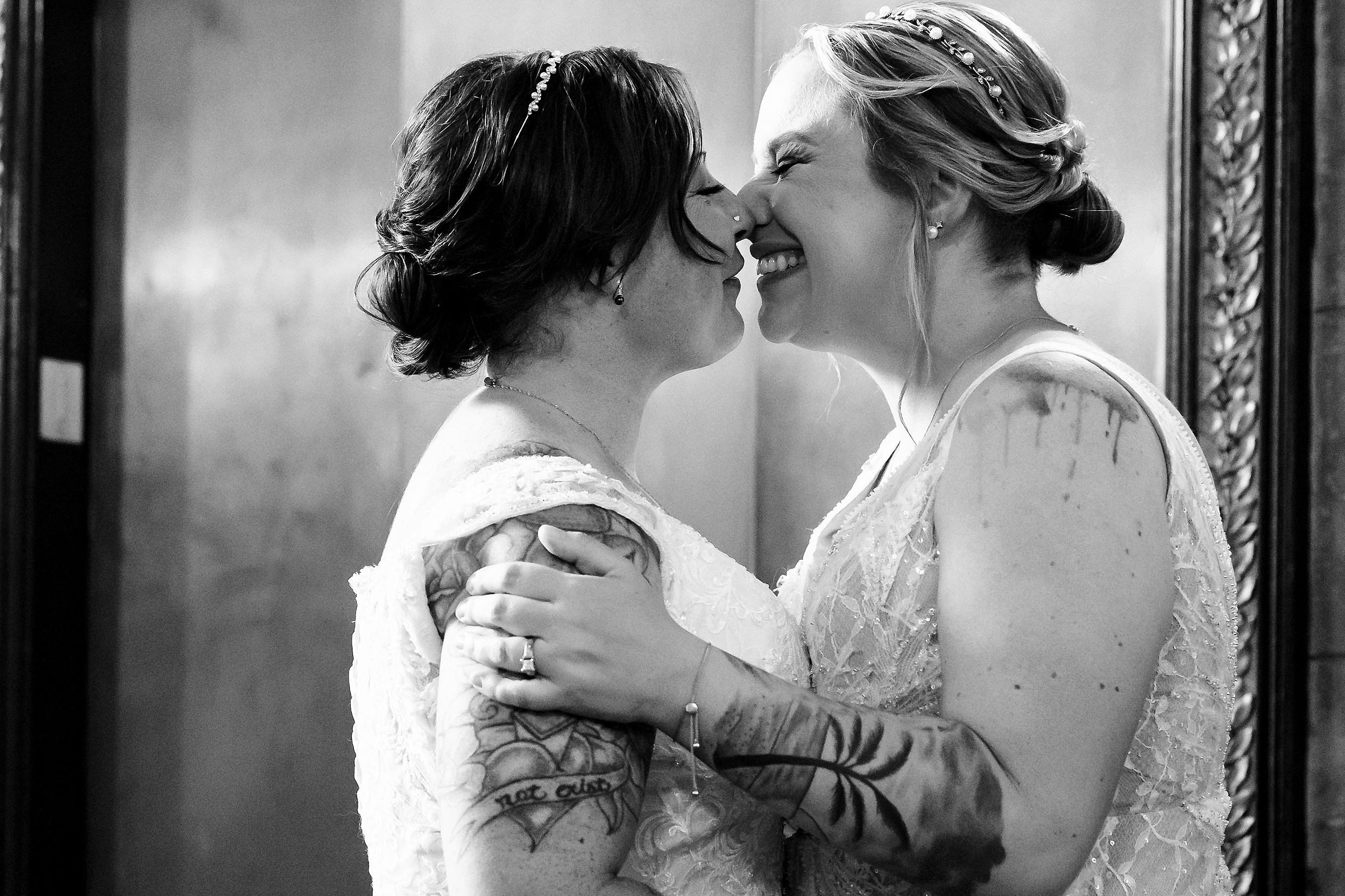 Newlyweds squish their noses while hugging in an elevator in lace dresses