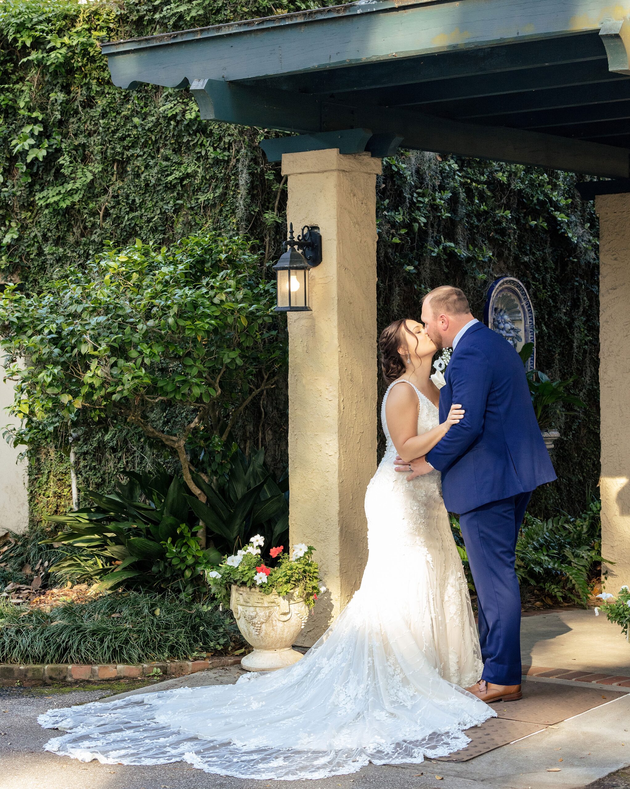 Newlyweds kiss in a blue suit and long lace dress at one of the beautiful st augustine garden wedding venues