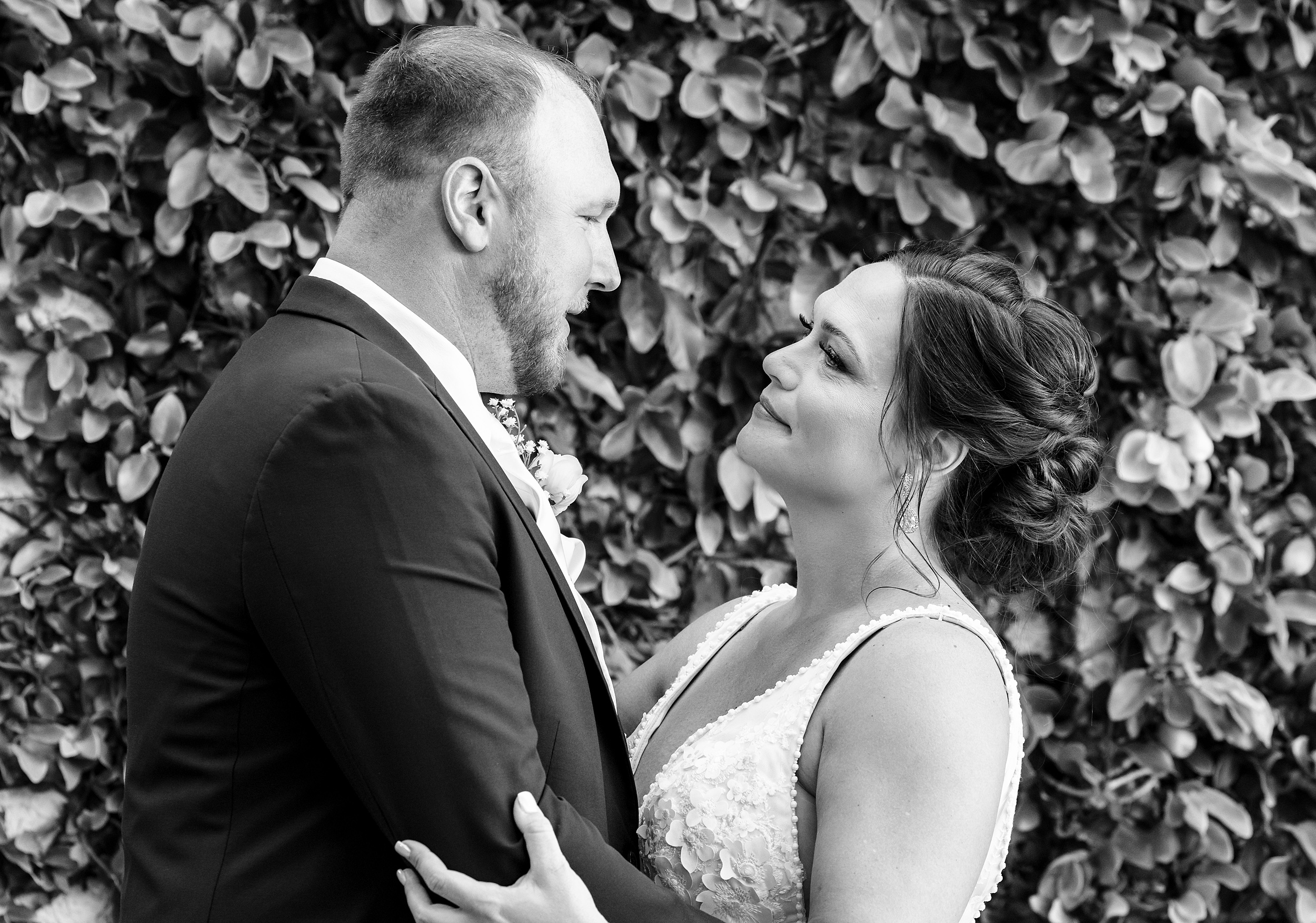 Newlyweds stare into each other's eyes in front of a greenery wall at a the palencia club wedding