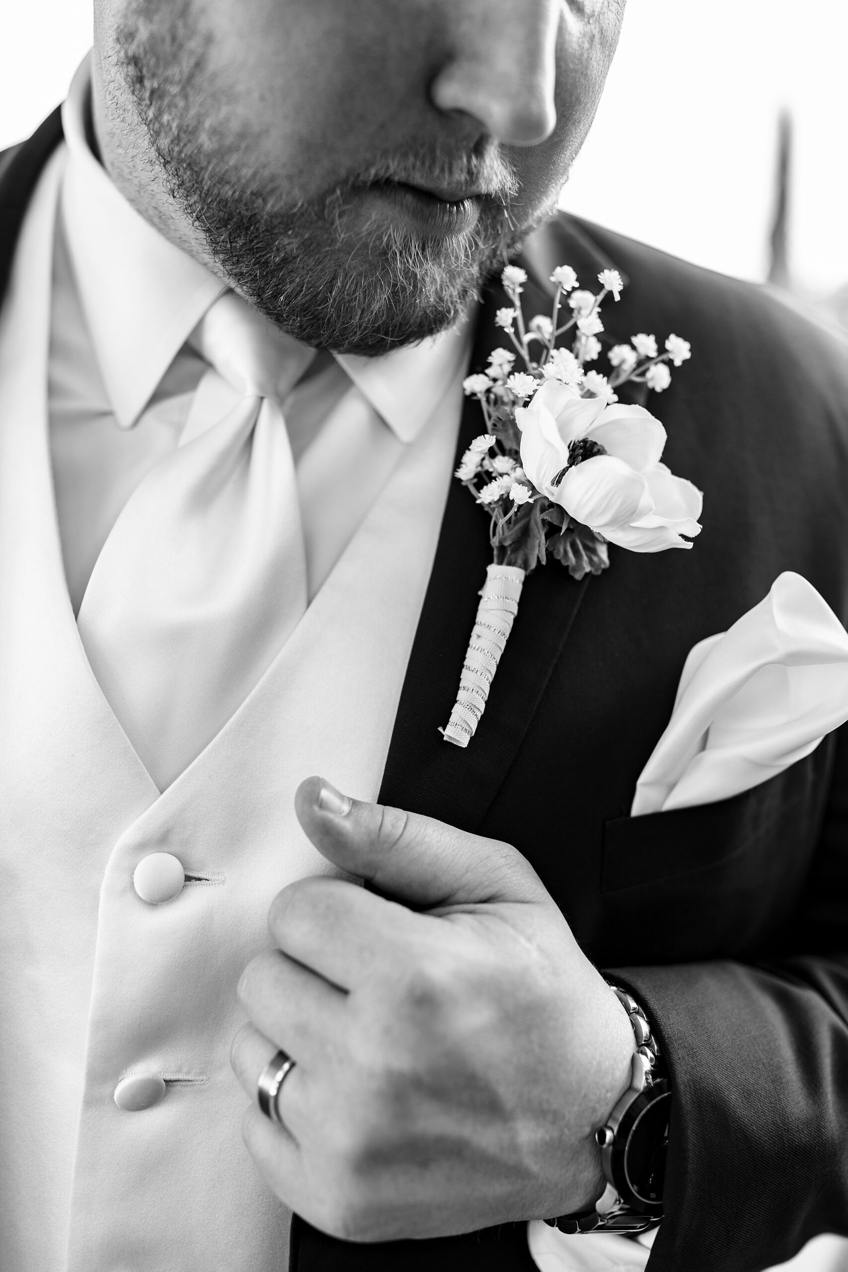 Details of a groom holding his lapel with a boutonniere at his the palencia club wedding