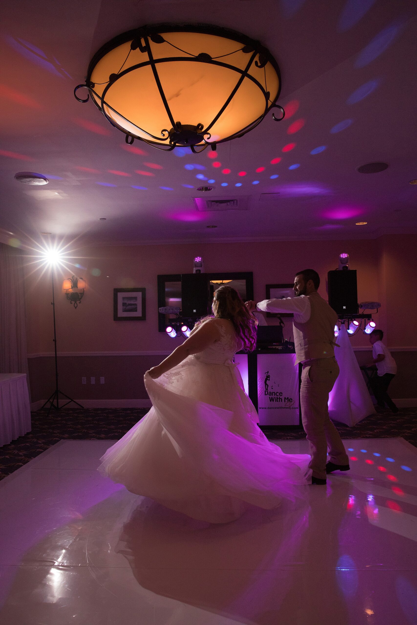 Newlyweds dance and twirl under purple lights in a ballroom for the first time
