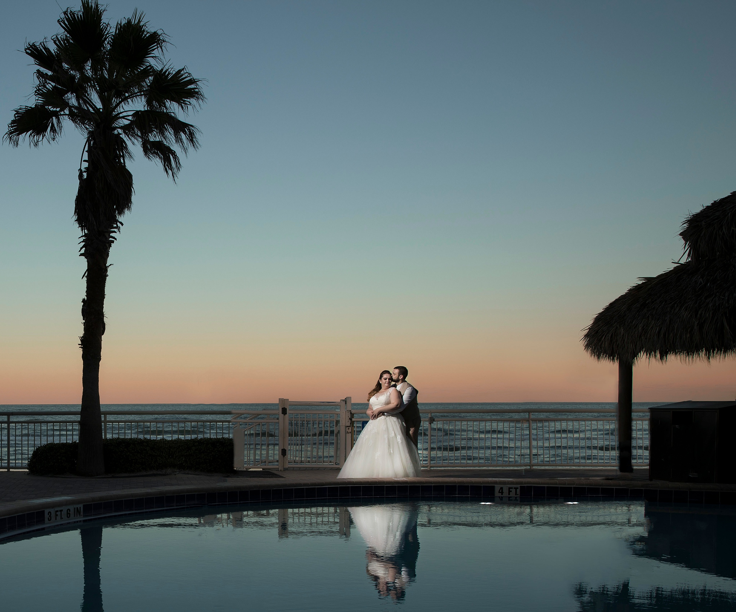 Newlyweds share a quiet poolside moment together at a beachfront hotel at sunset