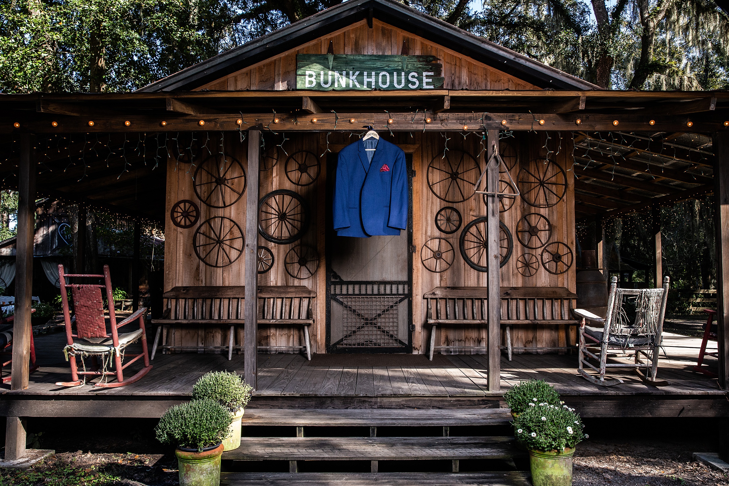A groom's suit jacket hands on a porch of the Bunkhouse at a tucker's farmhouse wedding