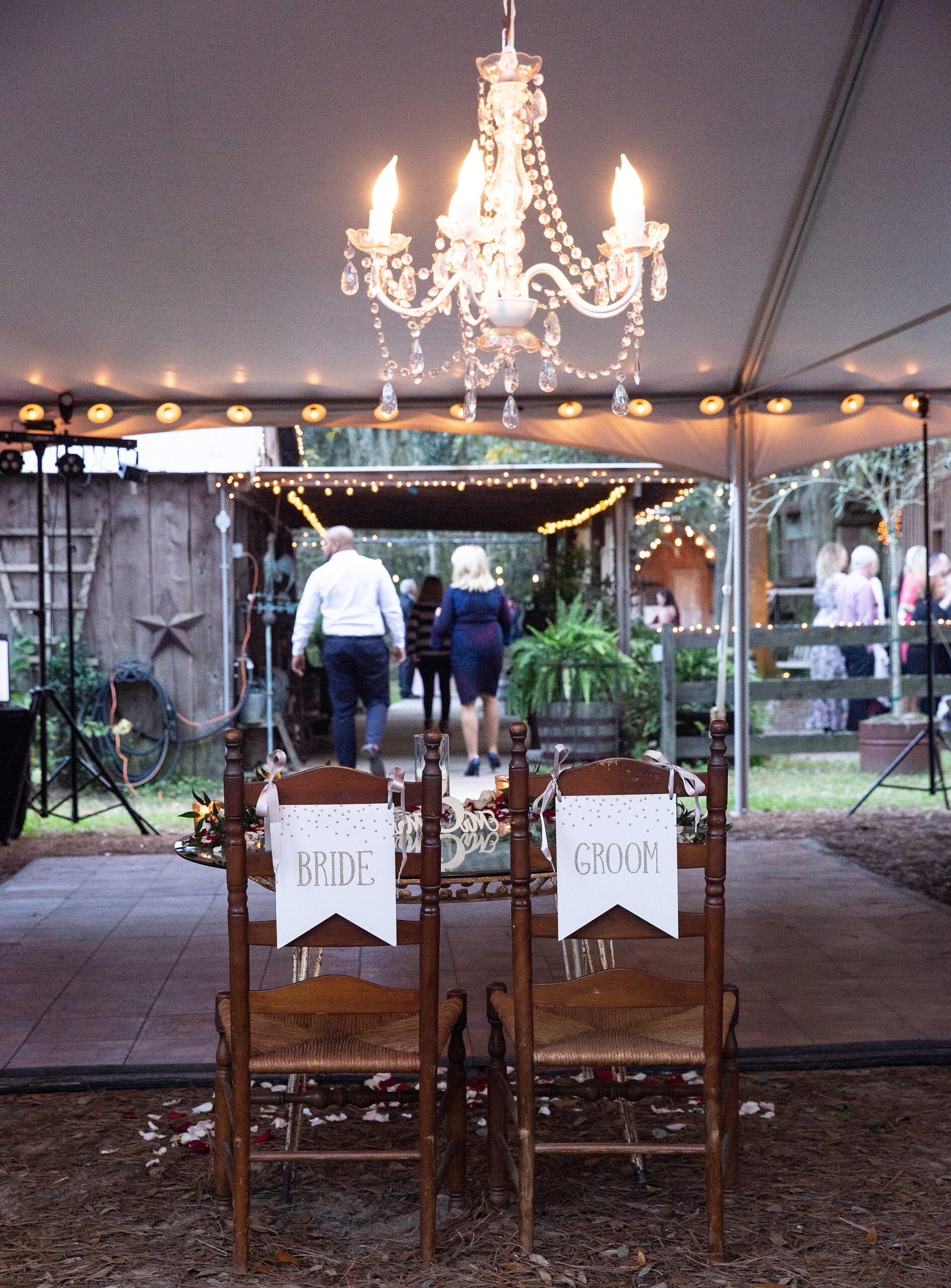 Details of a newlywed's head table at their tucker's farmhouse wedding reception under a tent and chandelier
