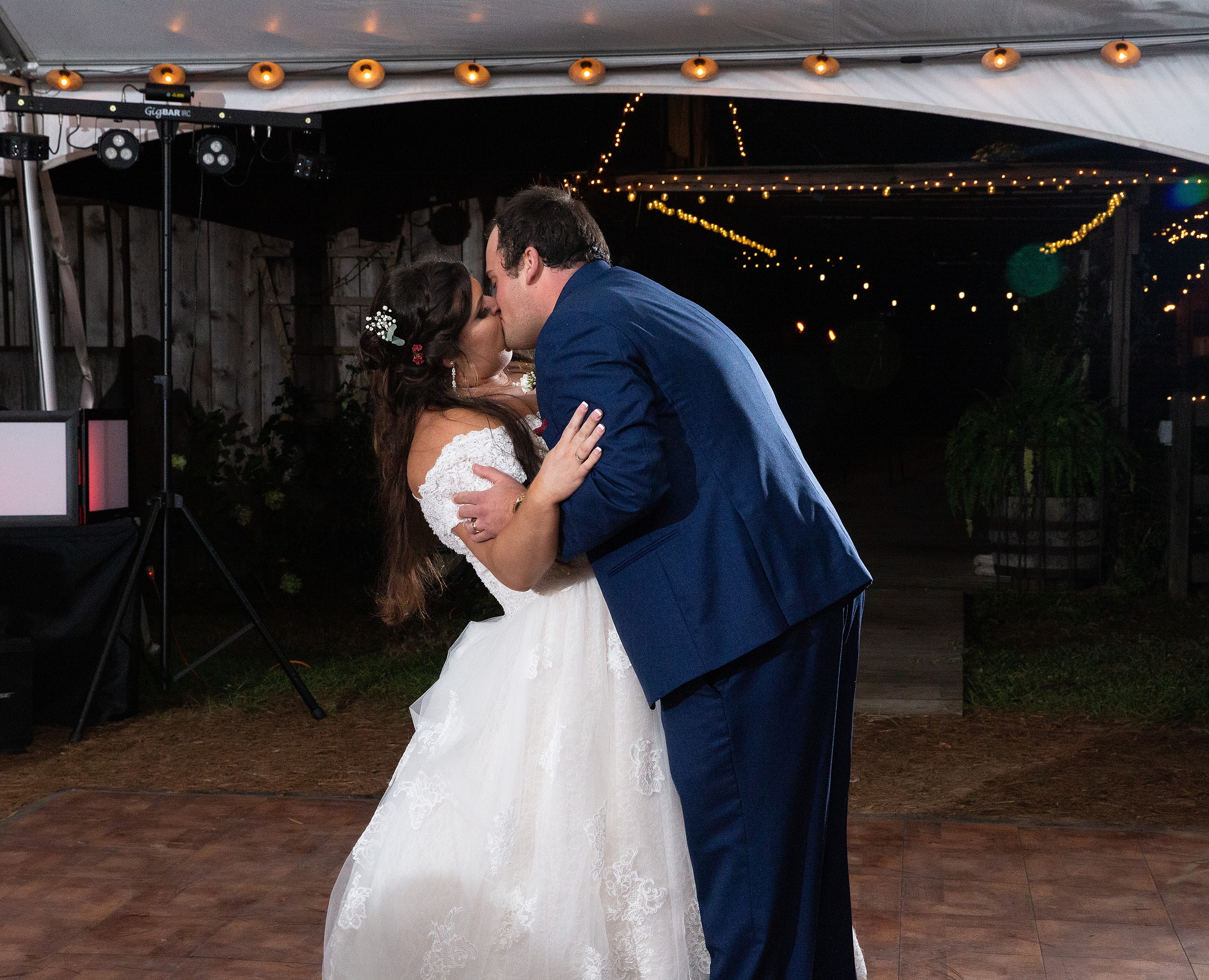 Newlyweds kiss during their first dance under a white tent Tucker's Farmhouse Wedding
